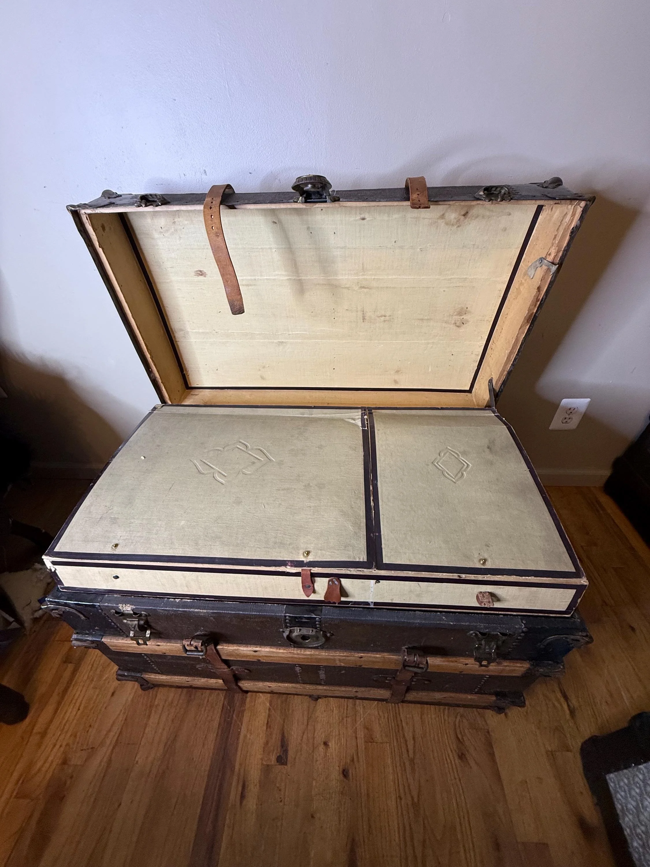 Inside view of an original antique trunk showing the historical paper lining and tray.