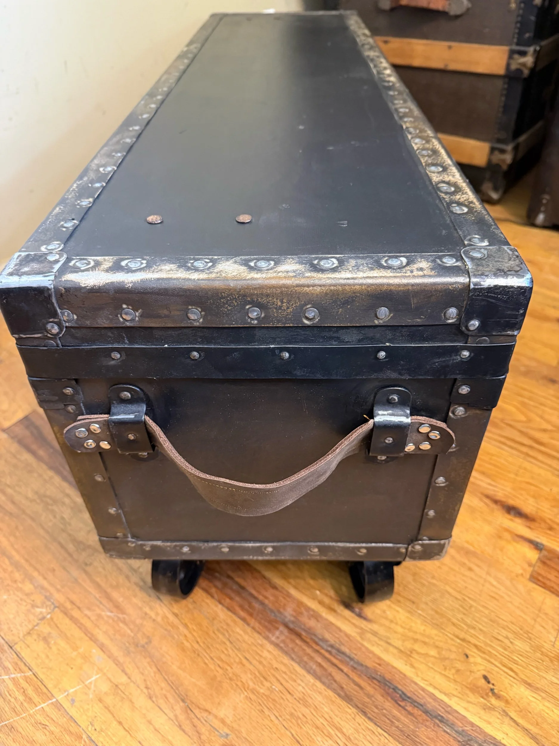 Side view of narrow antique trunk coffee table on wheels