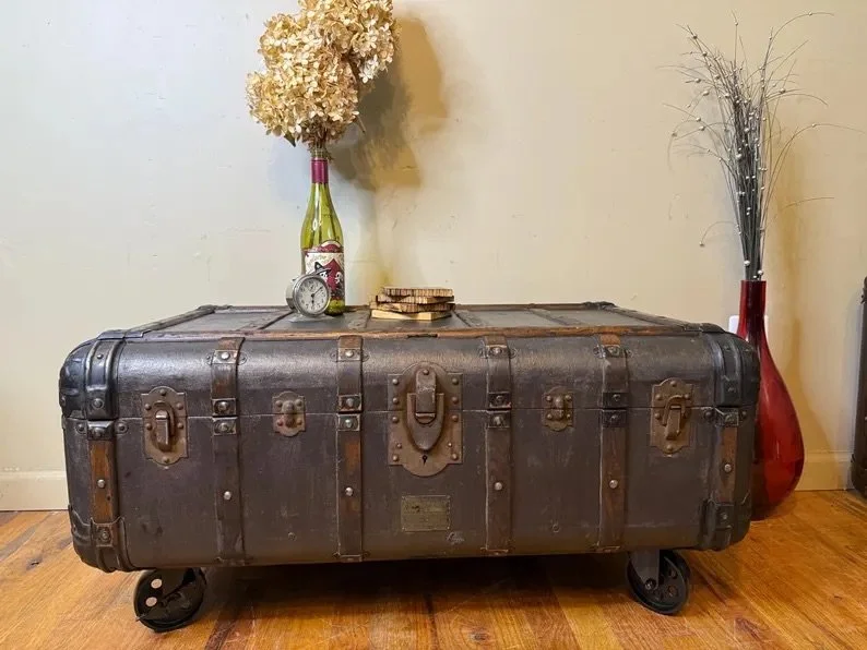 Large refinished flat top antique trunk used as an industrial storage coffee table