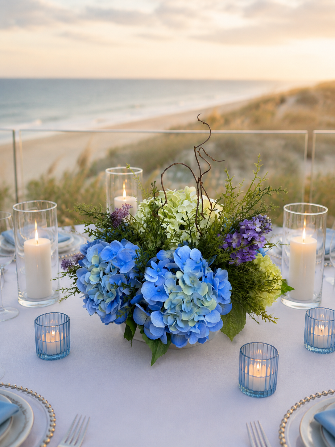 Coastal Centerpiece on white tablecloth with hurricane glasses & blue motive candles + blurred beach setting bkgnd.png