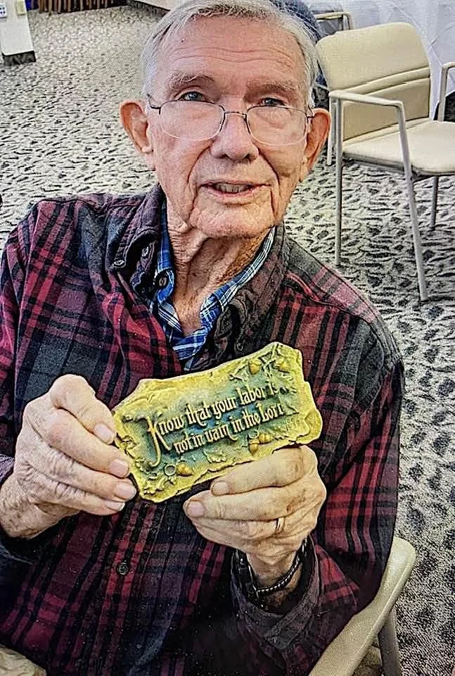 A.E. Mitchell's grandson David Mitchell holding a plaque. David passed away in 2025.