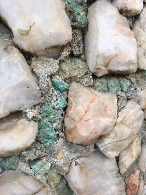 There are some beautiful colored rocks to be discovered in the crevices of the vase. Most of the rocks covering the surface are white or tan.