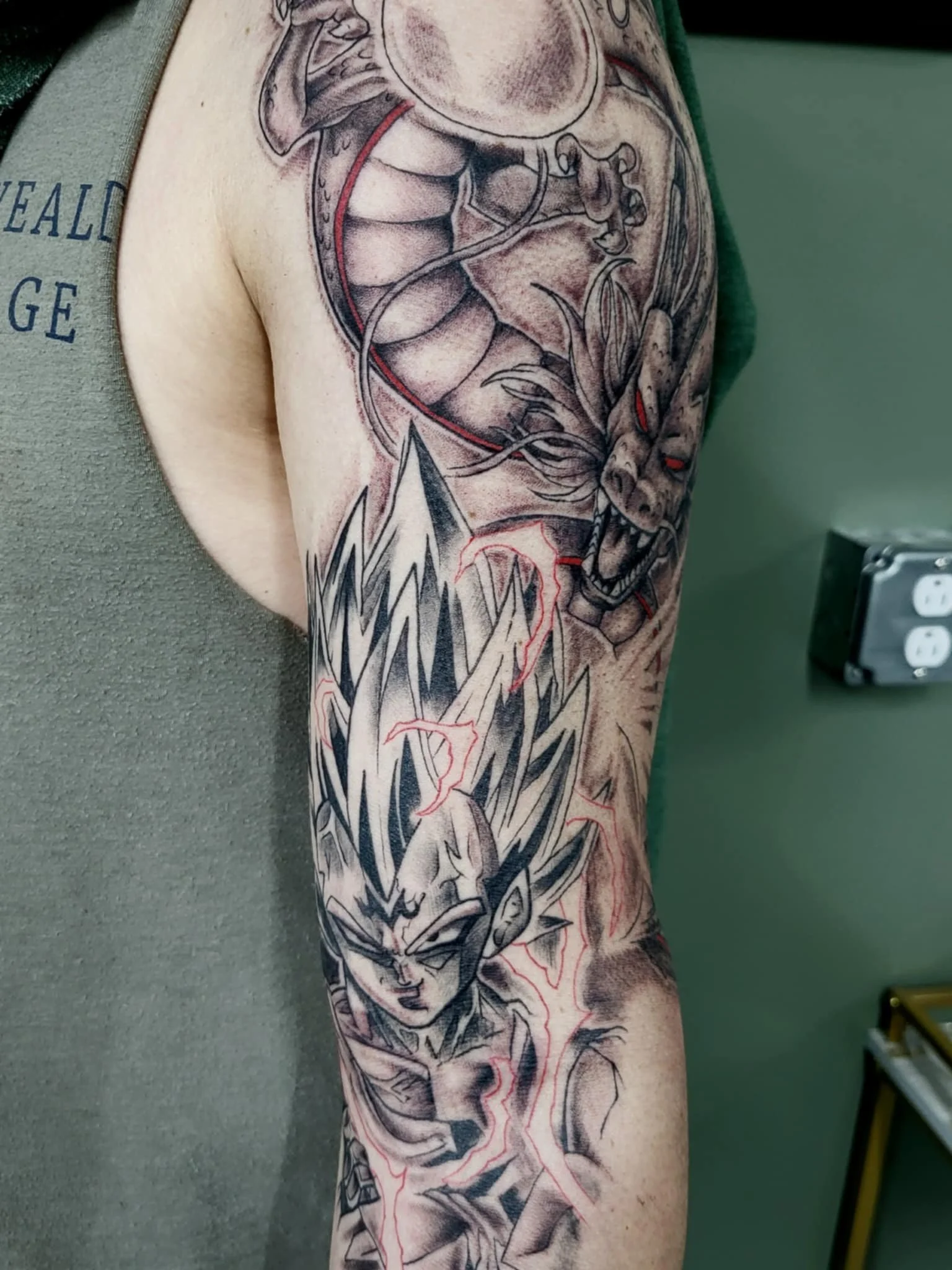 Tattoo of a dragon, a wolf, and electricity on a person's arm.