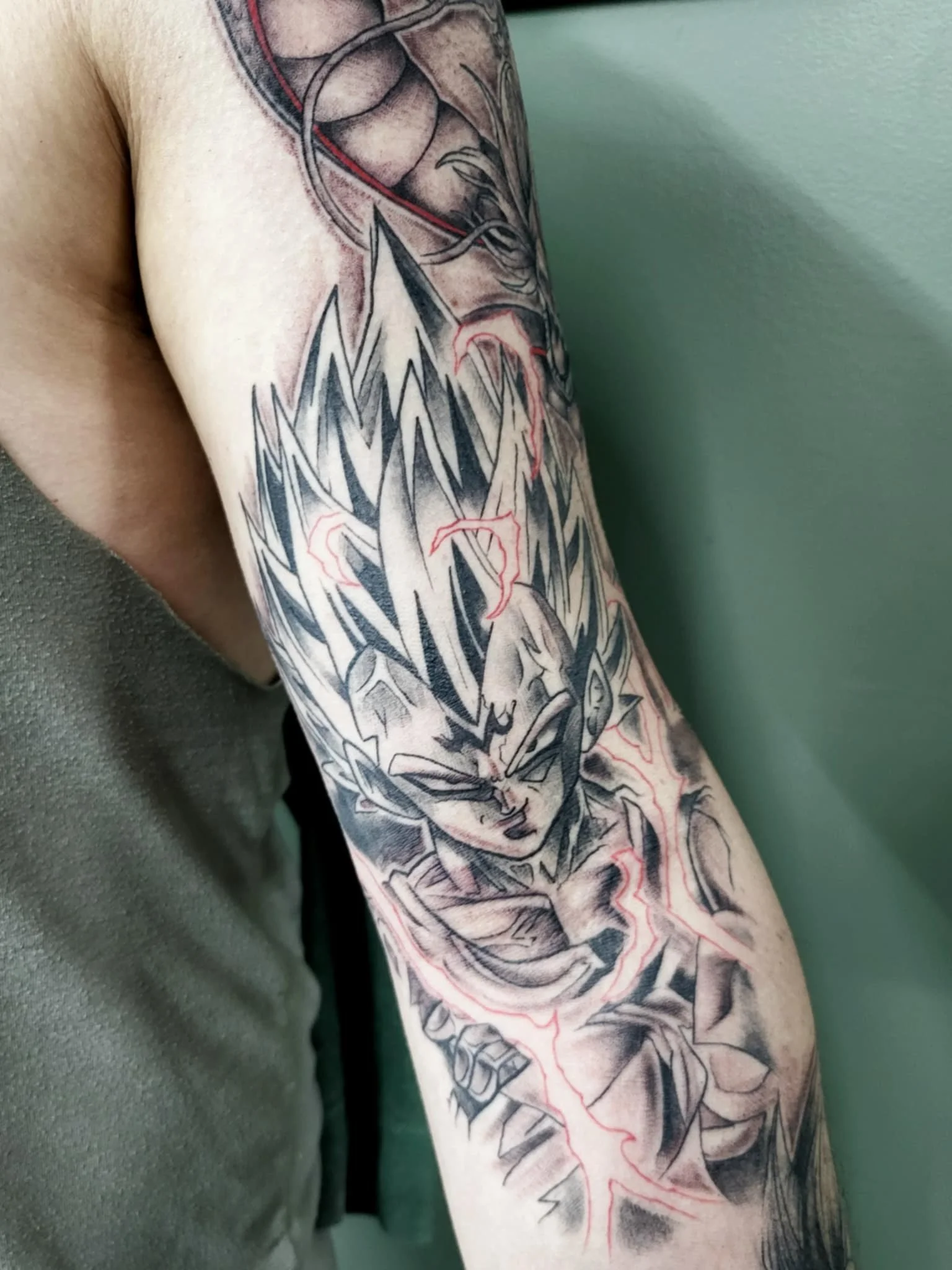 Tattoo of Goku from Dragon Ball Z with energy and lightning effects on a person's arm.