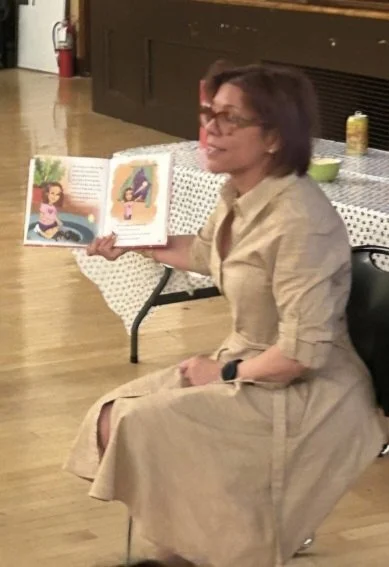 Vanessa Quiñones reading Her Heart Dog aloud, holding the open book up for her audience.