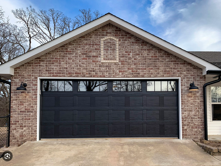 Brick house garage with black door and exterior lights