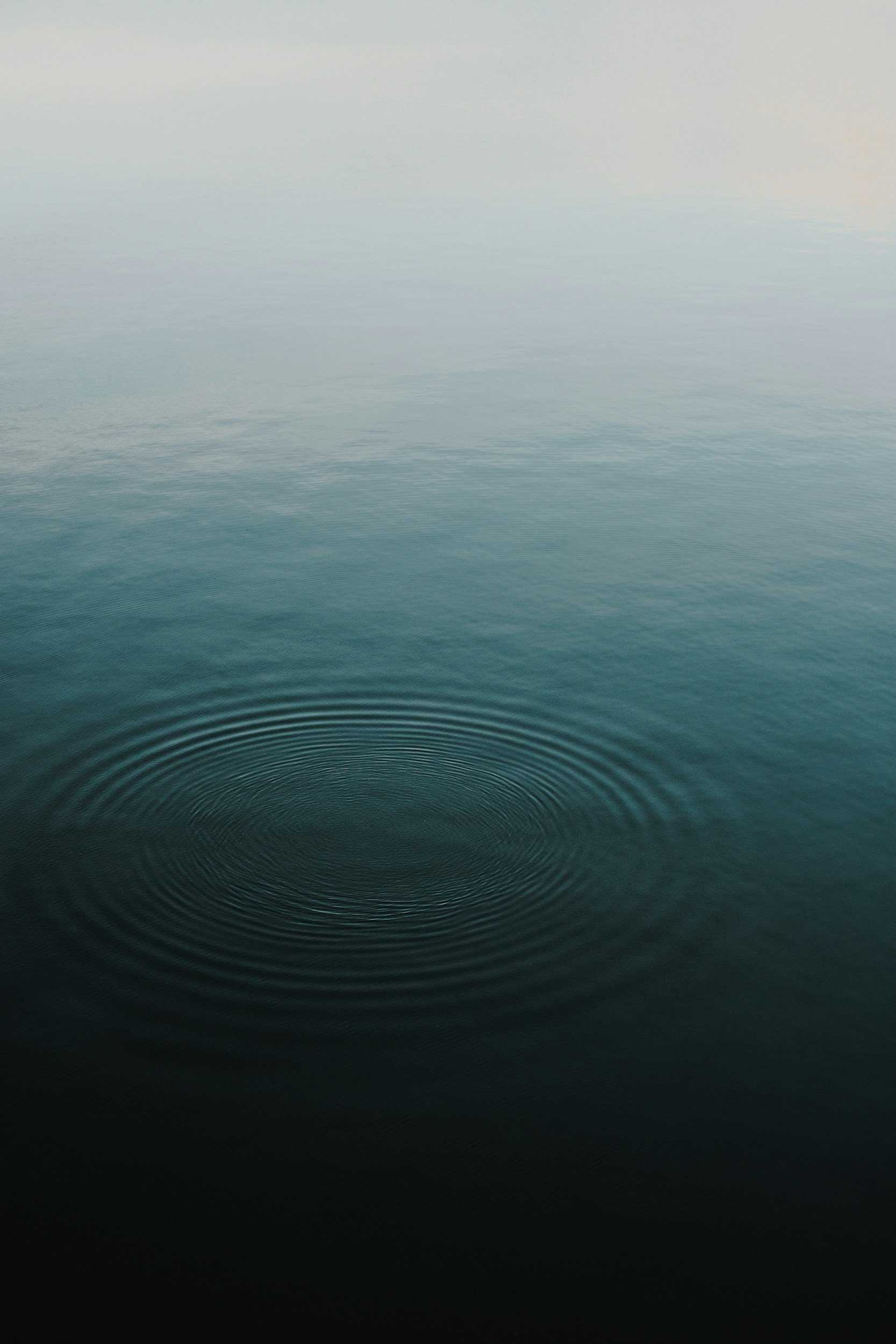 Calm ocean water with a gentle ripple pattern and a small circular ripple at the bottom center of the image.