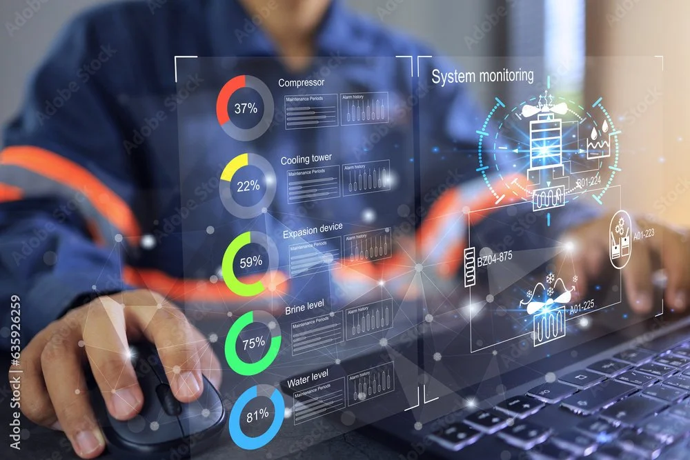 Person using a computer with holographic interface displaying system monitoring data, including compressor, cooling tower, expansion device, brine, and water levels, with various charts and icons.