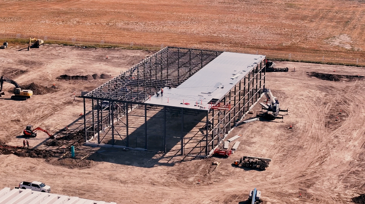 Aerial view of a steel frame going up on open prairie.