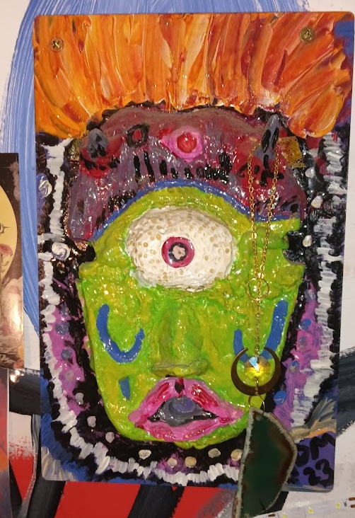 Abstract colorful painting of a face with a single large eye, pink lips, and vibrant colors including orange, purple, green, black, and white.