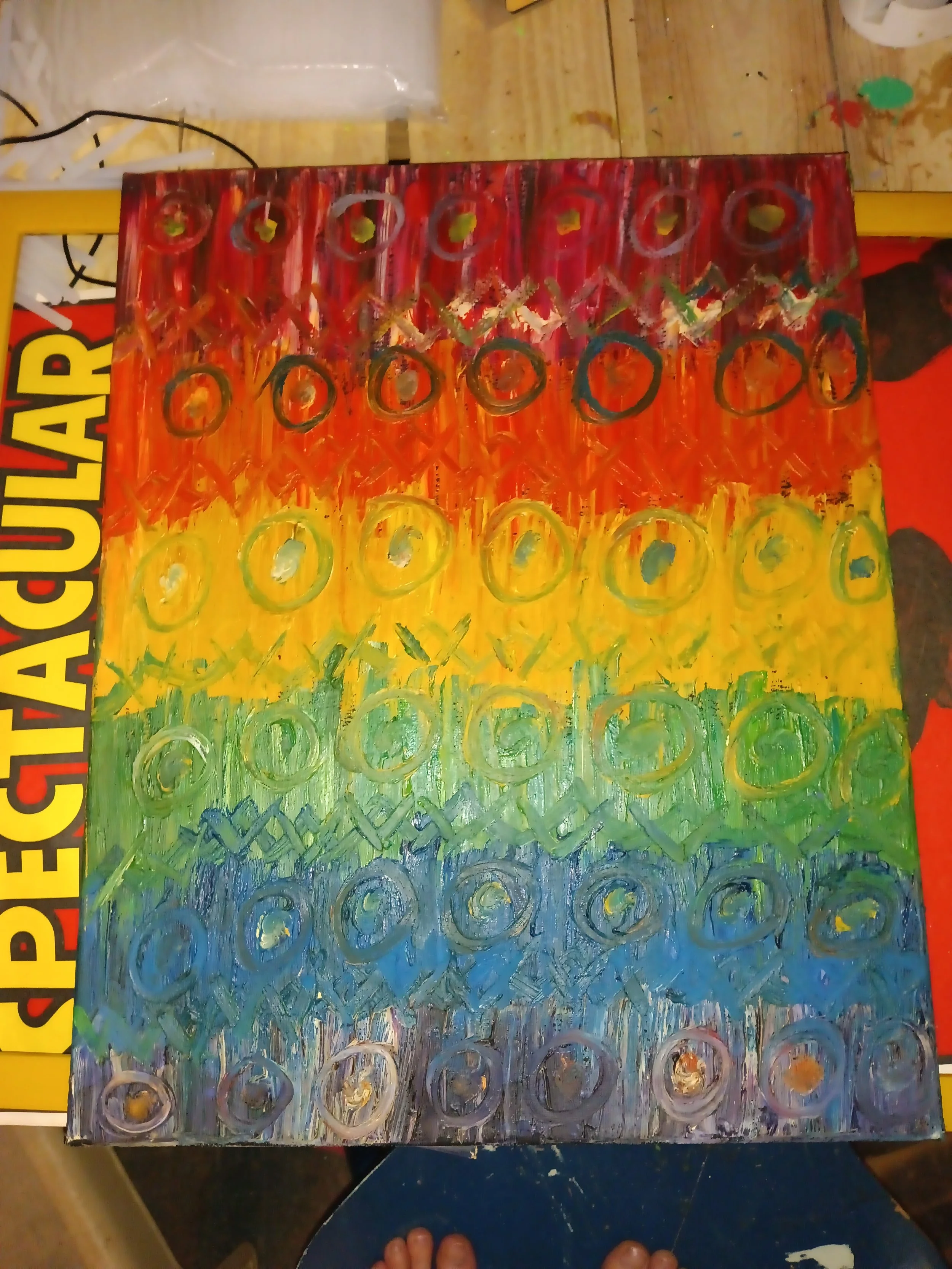 Colorful abstract painting with rainbow stripes of red, orange, yellow, green, blue, and purple, featuring repeated circular patterns.