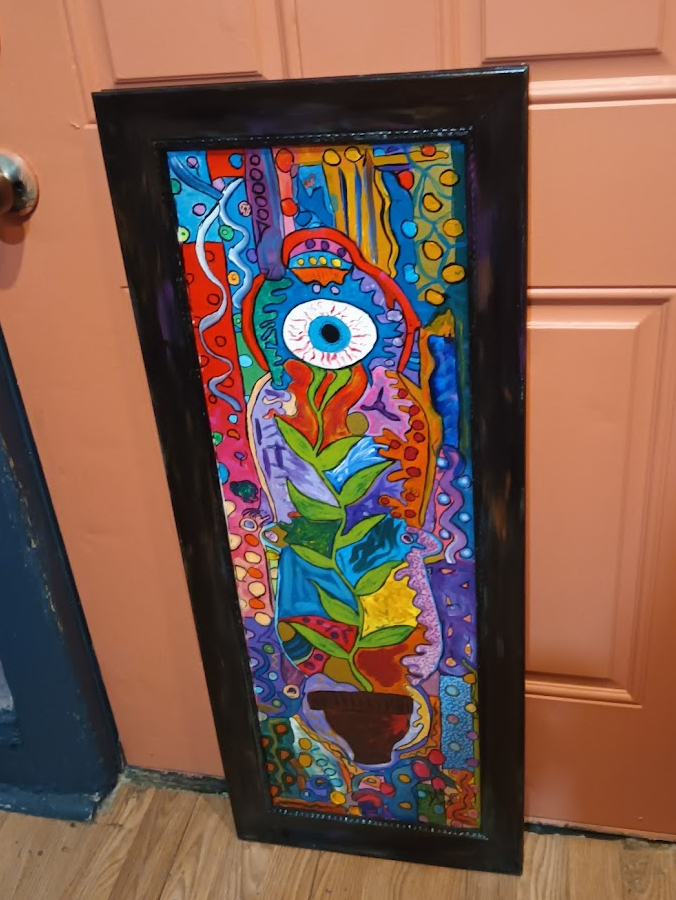 Colorful abstract painting of a potted plant with a large eye at the top, surrounded by vibrant shapes and patterns in red, yellow, blue, purple, and green, framed in black.