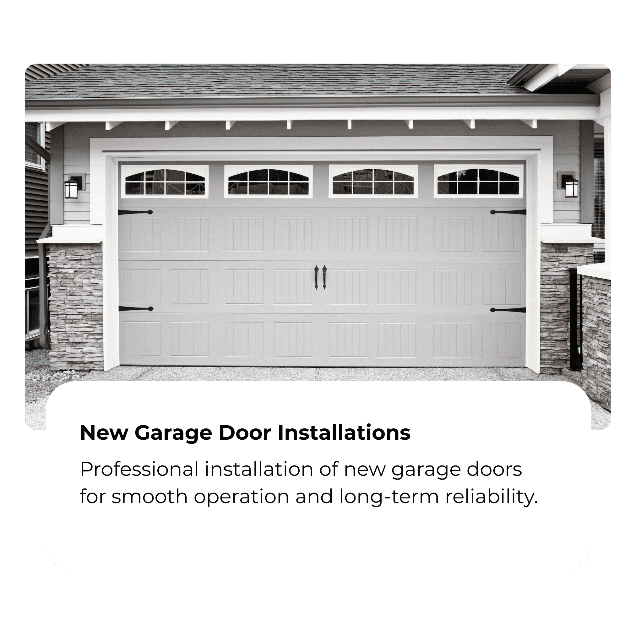 A white garage door with windows at the top, mounted on a house with gray siding and stone accents. There are two wall-mounted lantern lights beside the garage door.