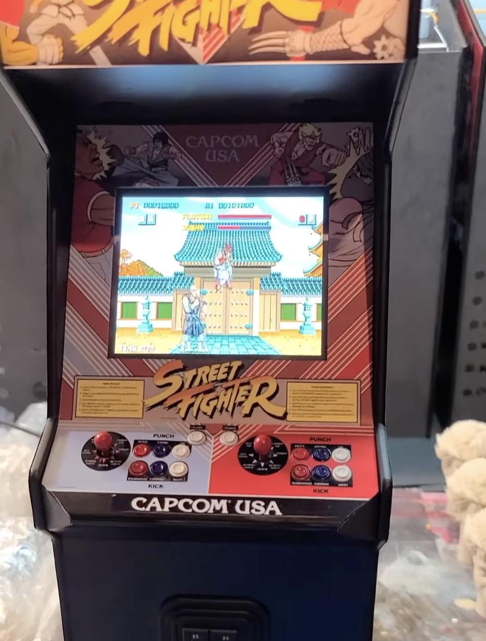Arcade game cabinet featuring a Street Fighter video game with a colorful design and a screen showing characters fighting in front of a traditional Asian building.