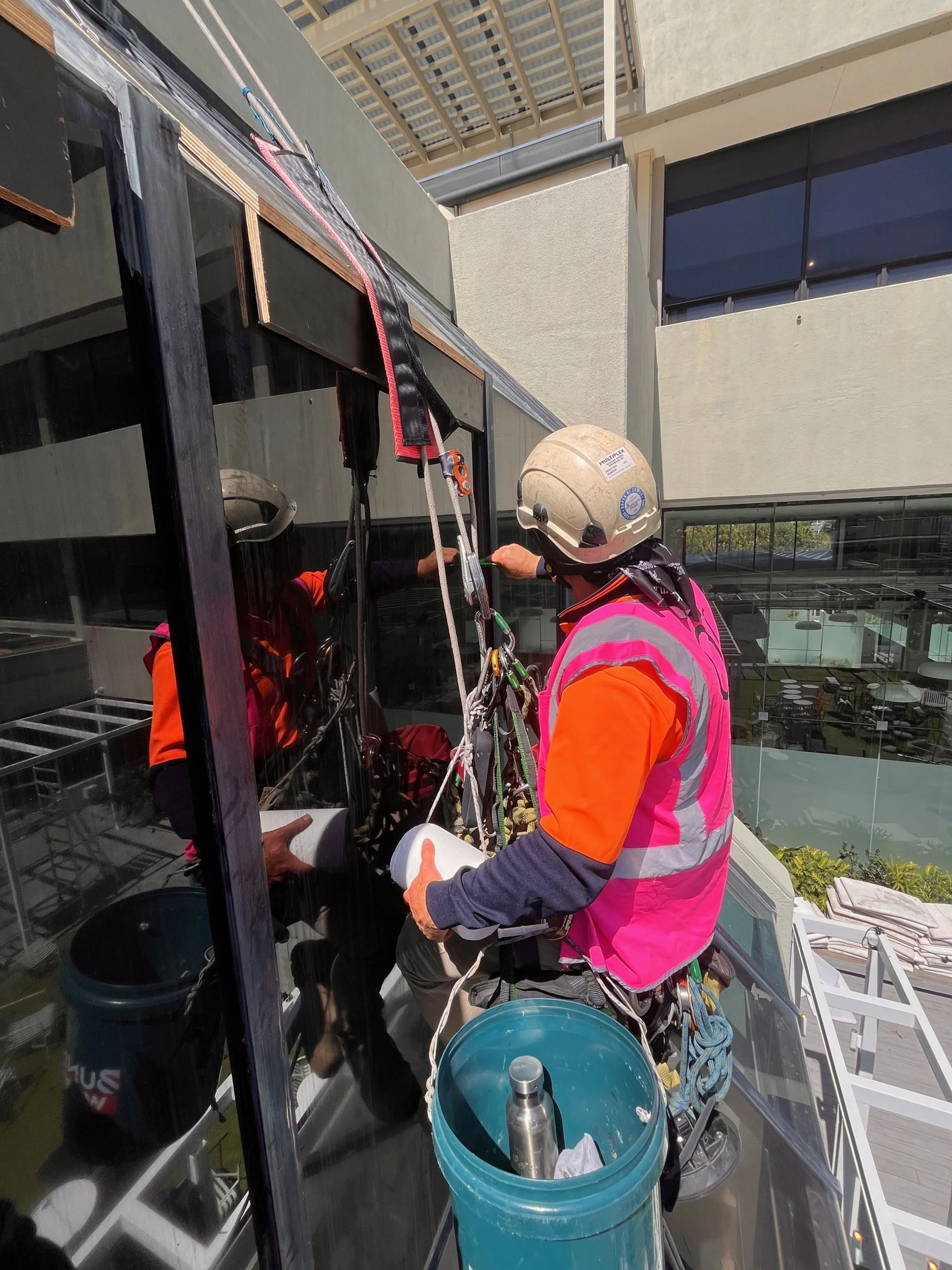Glazier in safety gear installing glass on a building exterior.