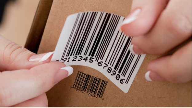 Person applying a barcode sticker to a cardboard box.