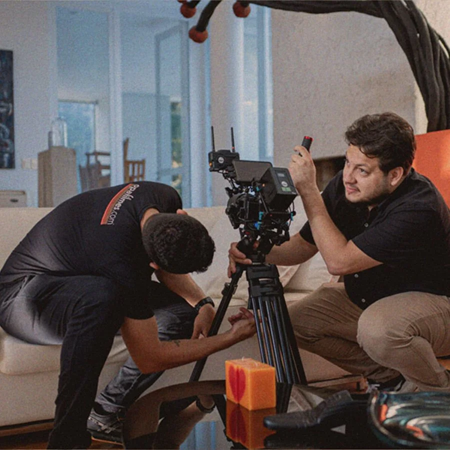 Duas pessoas ajustando uma câmera de filmagem em uma sala de estar.