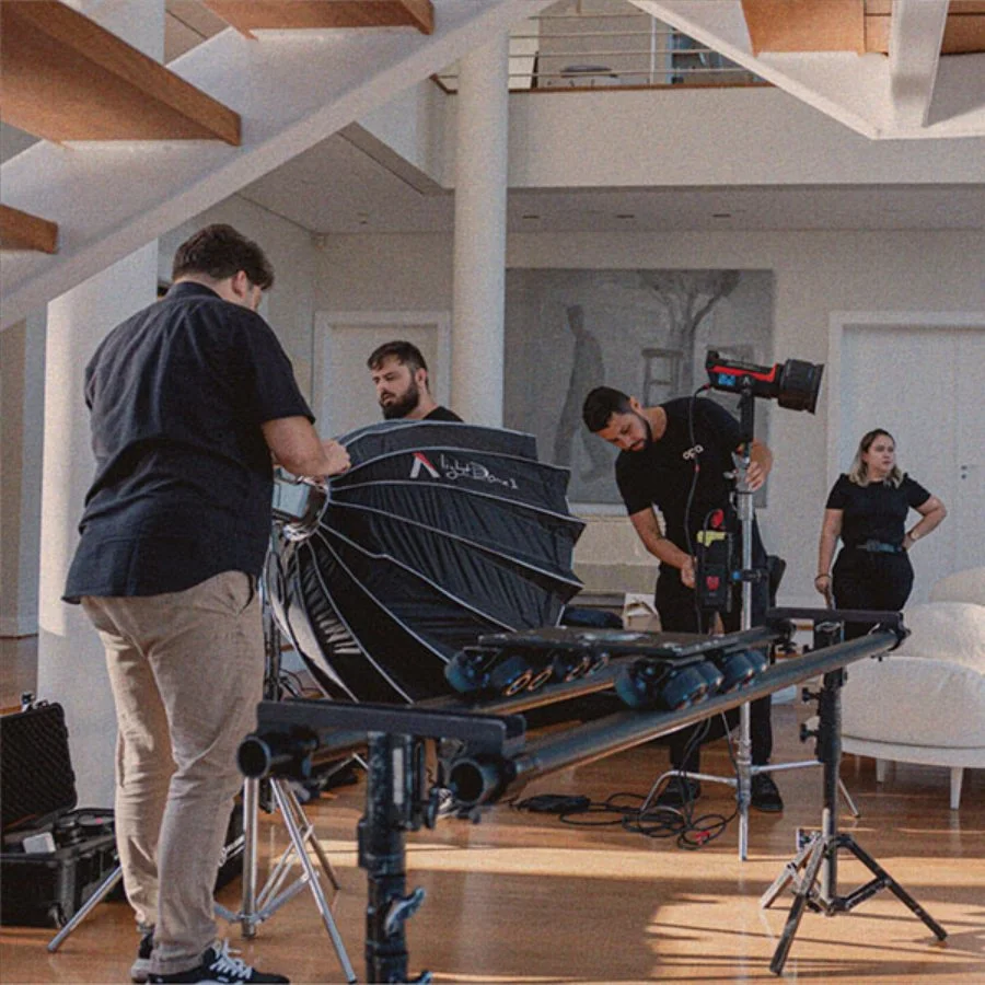 Equipe de fotógrafos ajustando equipamentos de iluminação e câmera em um ambiente interno, possivelmente para uma sessão de fotos ou filmagem.