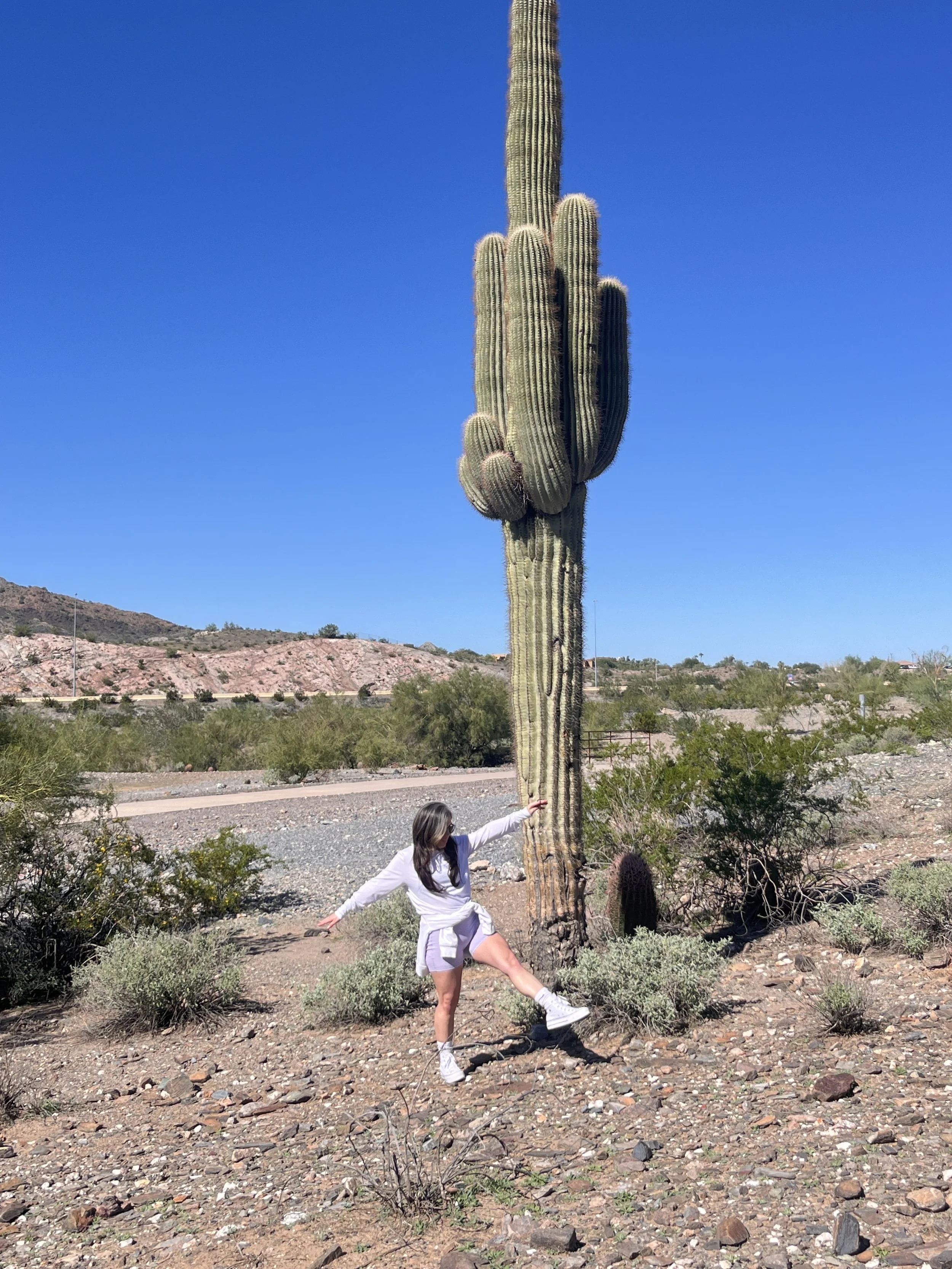 women walking by a giant cactus in desert