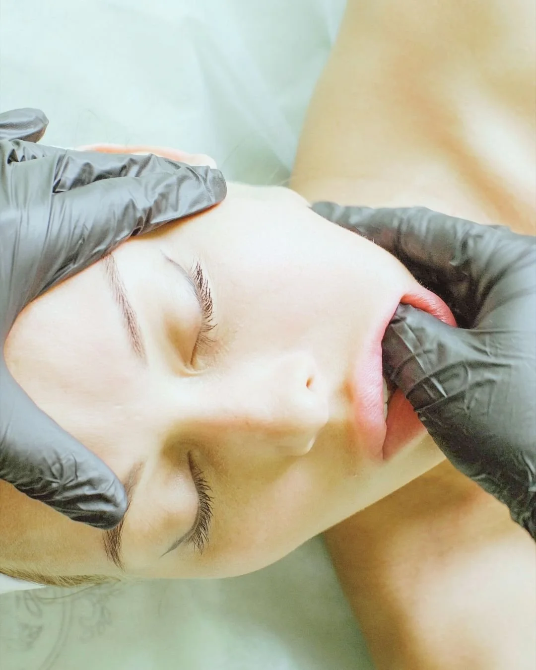 women wearing black gloves and doing buccal massage on a women for tension release in her jaw