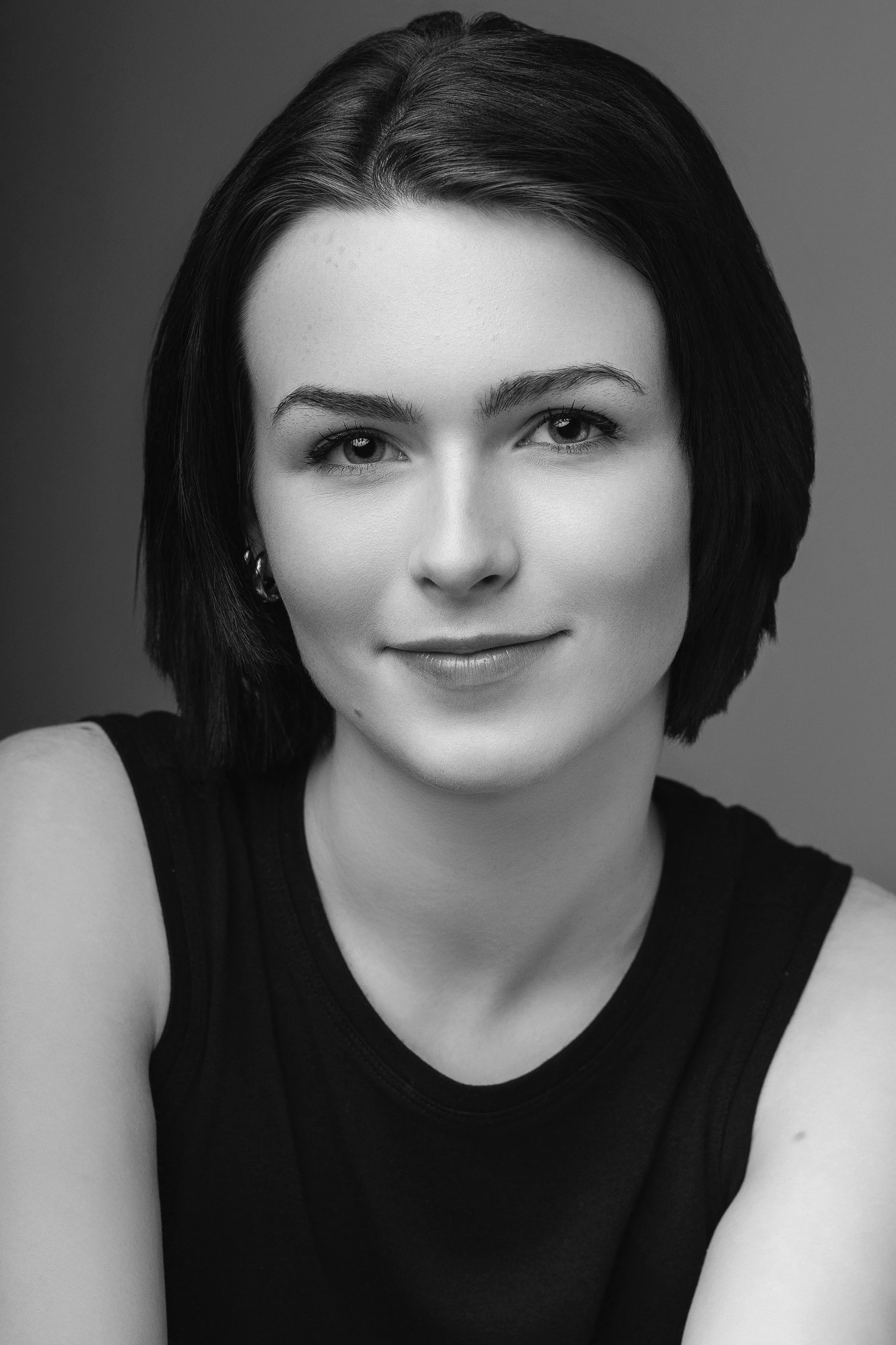 Black and white portrait of a woman with short dark hair, smiling slightly, wearing a sleeveless top.