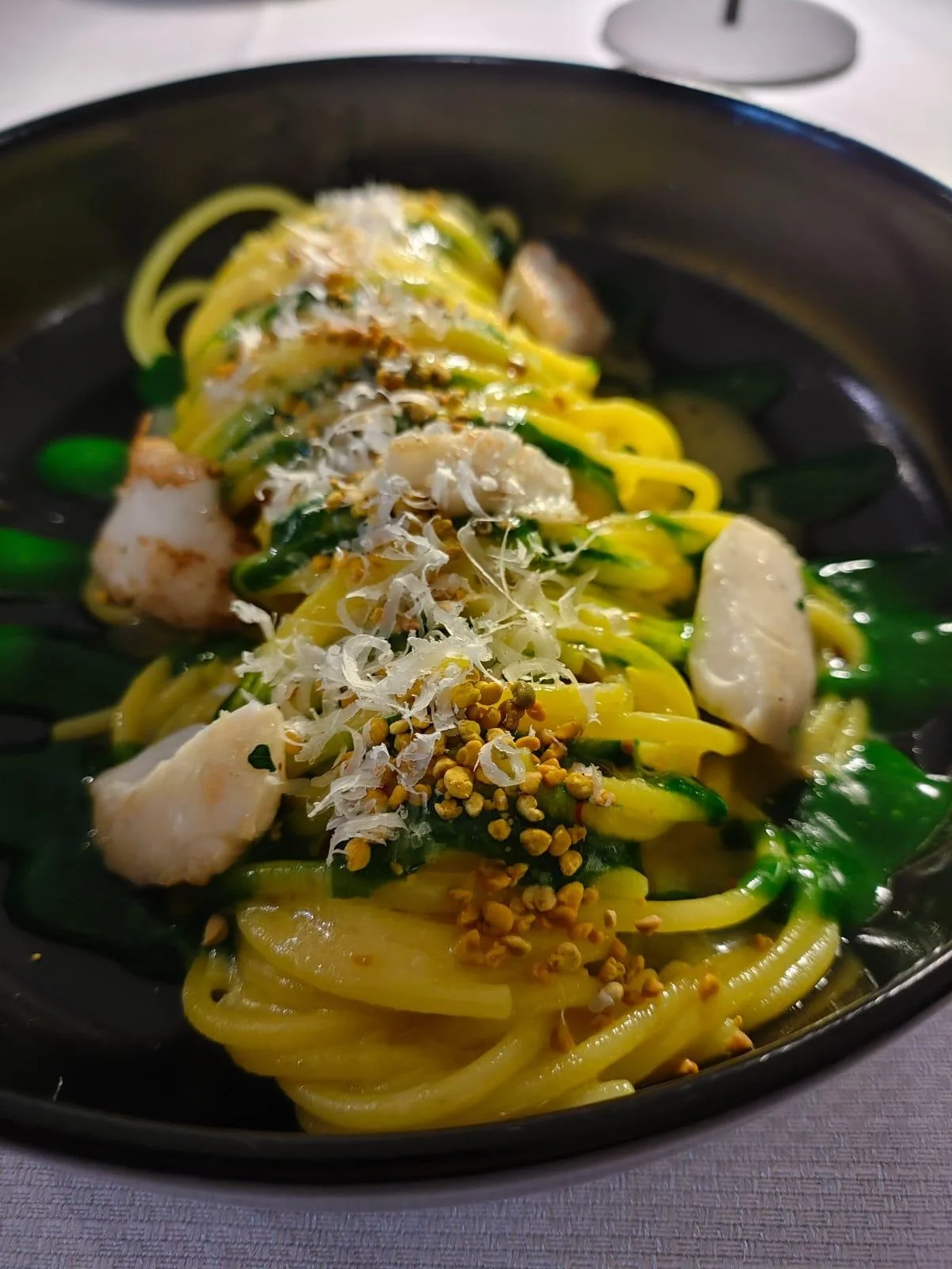 Piatto di spaghetti con zucchine, gamberi, formaggio grattugiato e semi di senape.