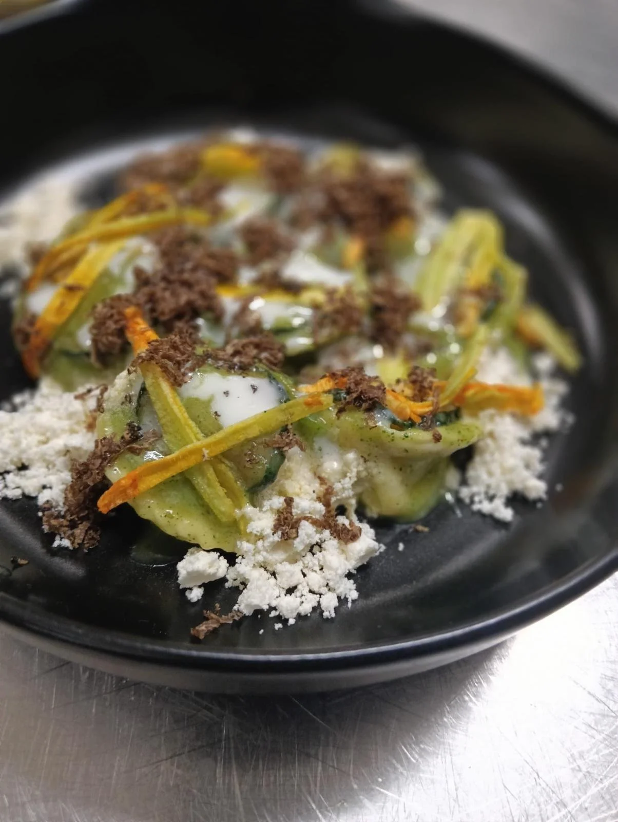 Piatto di pasta con verdure, formaggio grattugiato, carne e uova in un piatto nero
