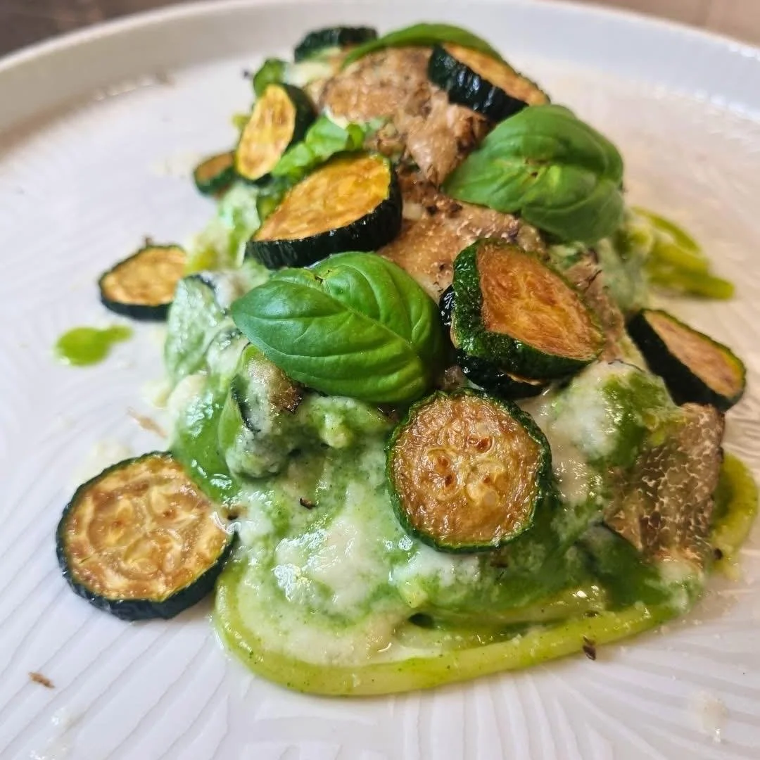 Piatti di pasta con crema verde, zucchine grigliate, foglie di basilico e mozzarella.