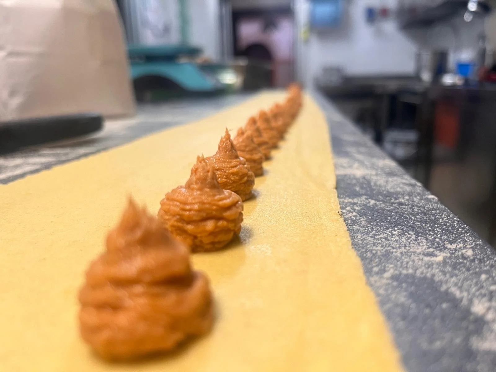 Tortellini di pasta fresca con ripieno di carne, disposti su un piano di lavoro in attesa di essere cucinati.