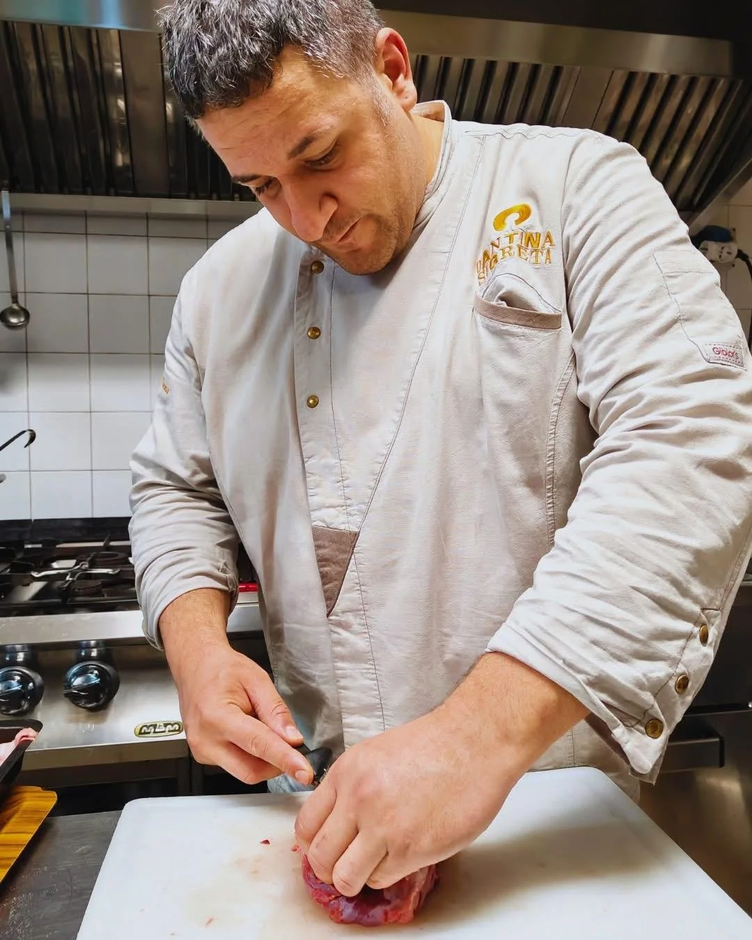 Chef che taglia la carne su un tagliere in cucina.