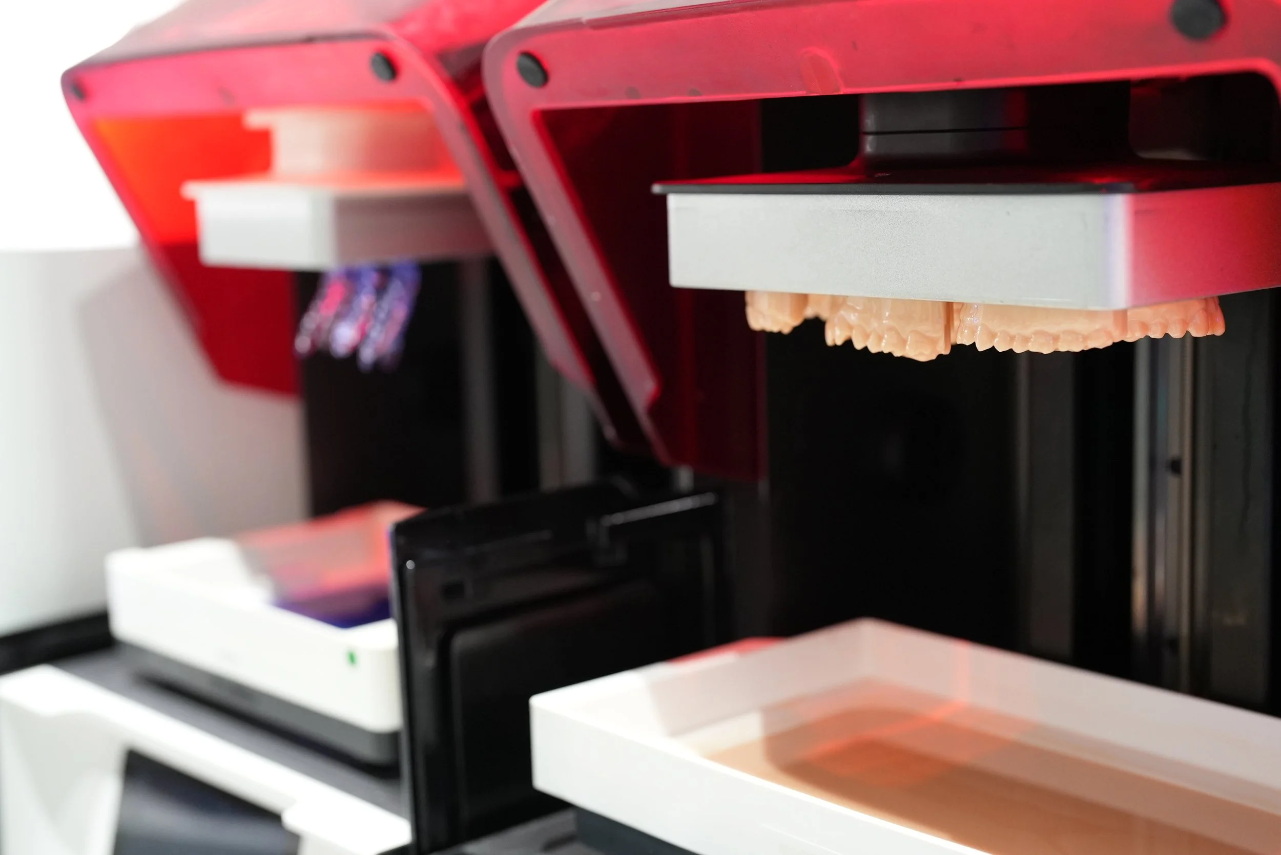 Close-up of a machine with a red top, dispensing a beige, tooth-like object onto a tray.