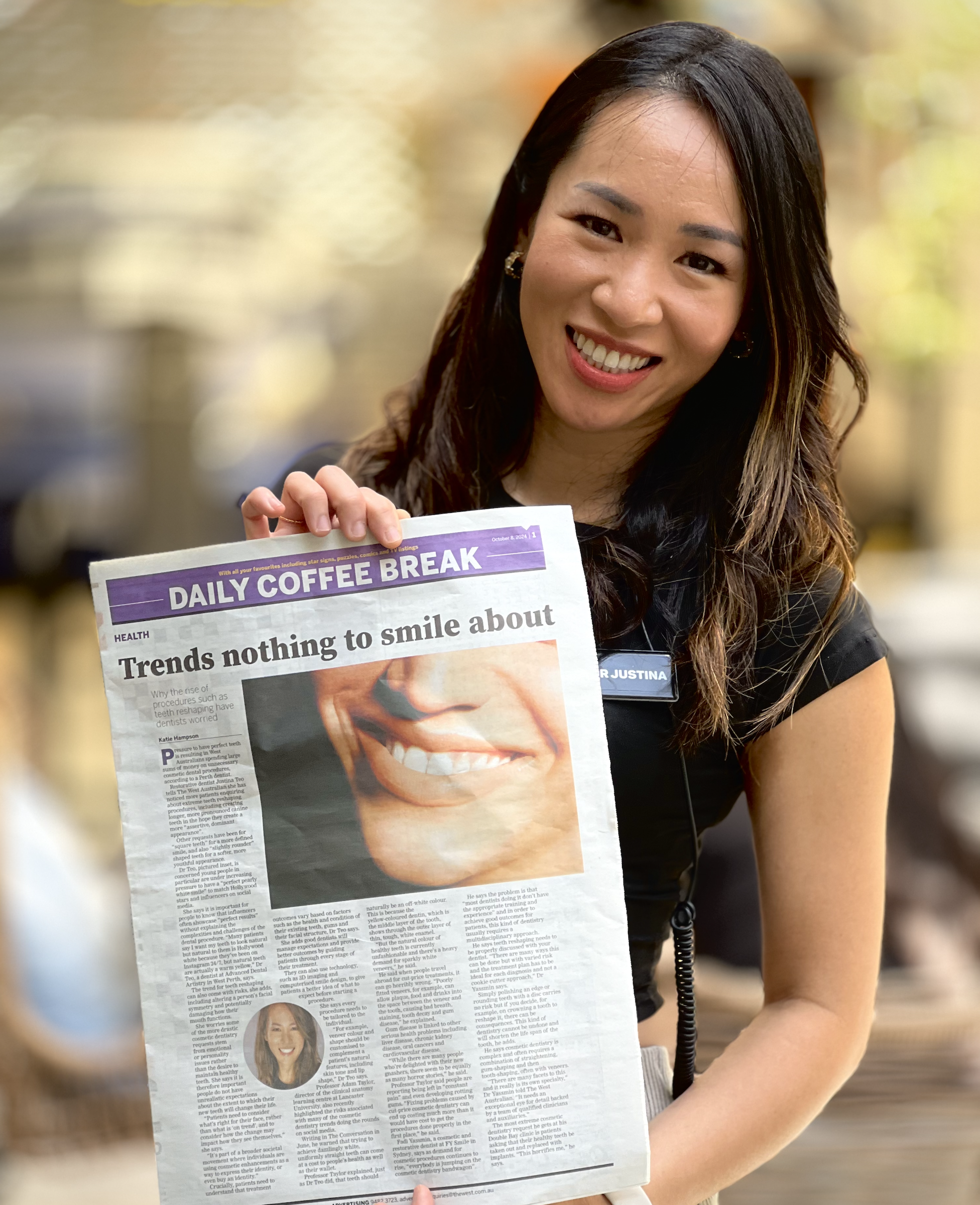 A woman smiling while holding a newspaper titled 'Daily Coffee Break' with a headline 'Trends nothing to smile about', in a setting that appears to be a coffee shop or cafe.