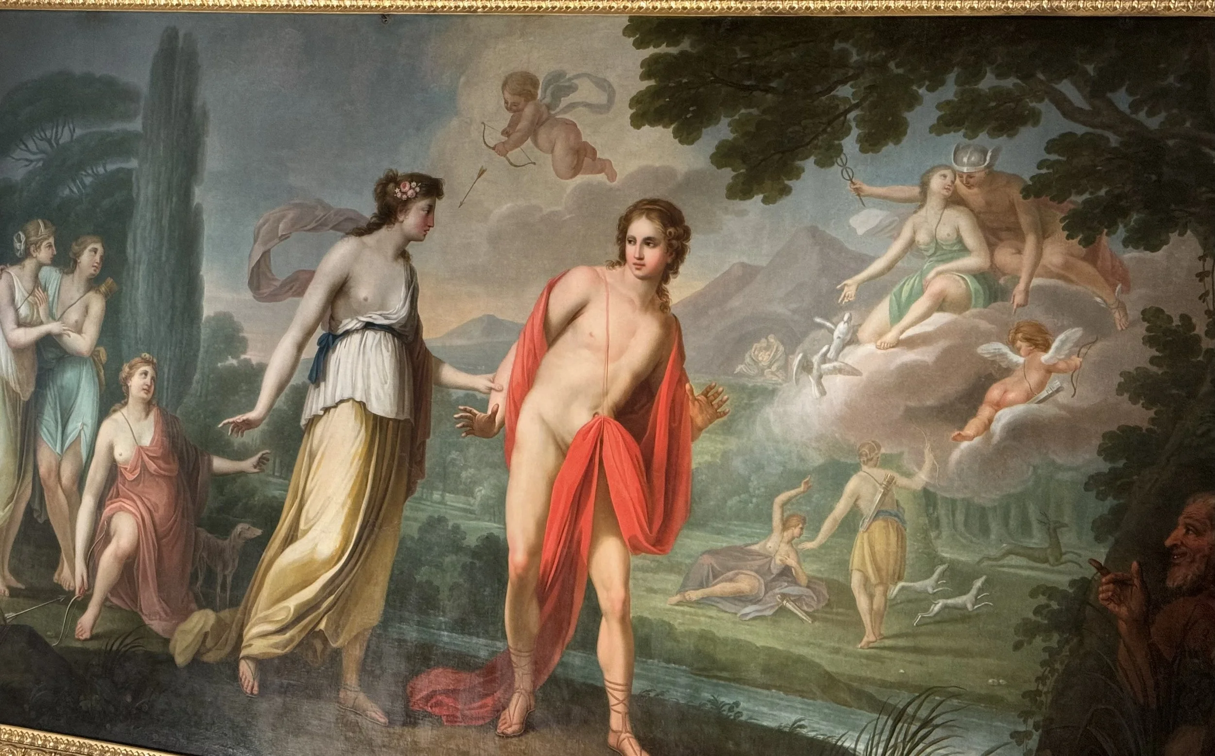 A classical painting depicting Greek mythology, with a central male figure with long hair and a red drape, surrounded by women and gods in a landscape with mountains, trees, and a river.