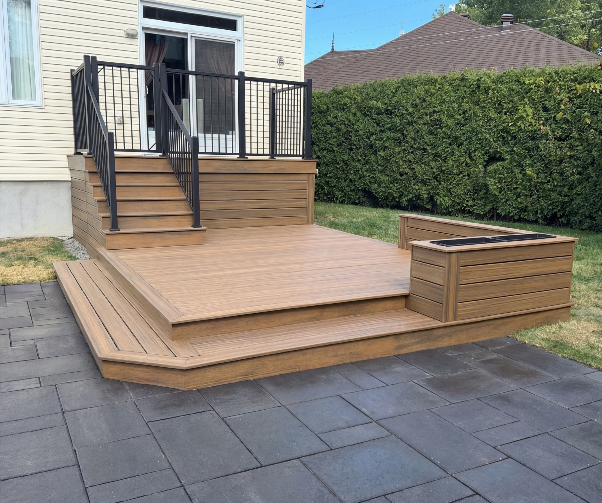  Terrasse donnant sur un deck muni d'un muret et bac à fleurs, le tout en composite. Rampes modernes en aluminium de haute qualité. 
