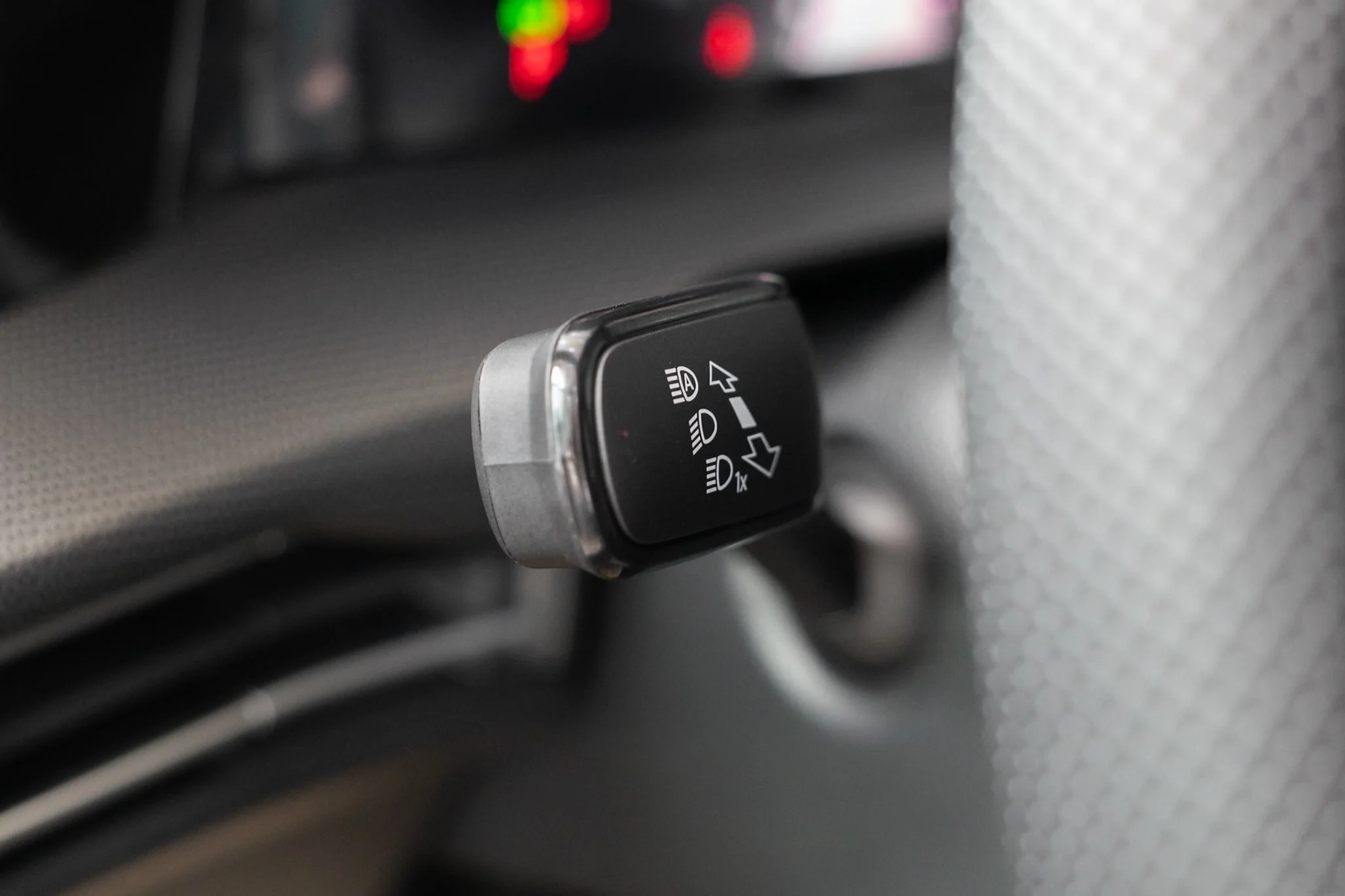 Close-up of a car headlight control switch mounted on a textured surface inside a vehicle.