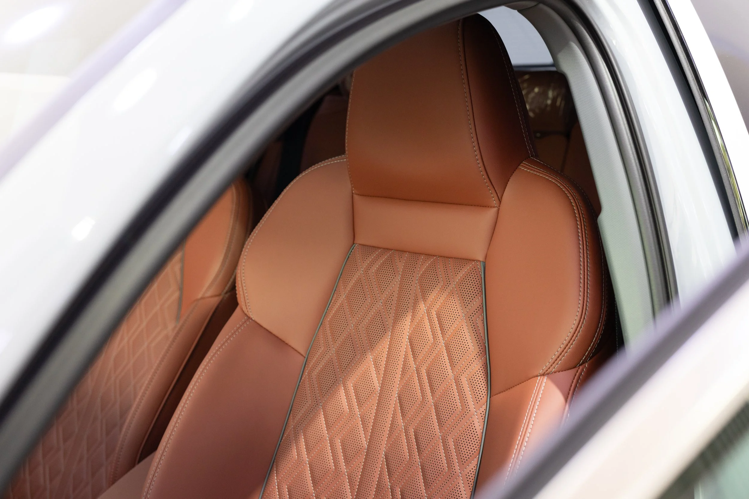 Close-up view of the interior of a vehicle, focusing on the tan leather seats with diamond quilted stitching.