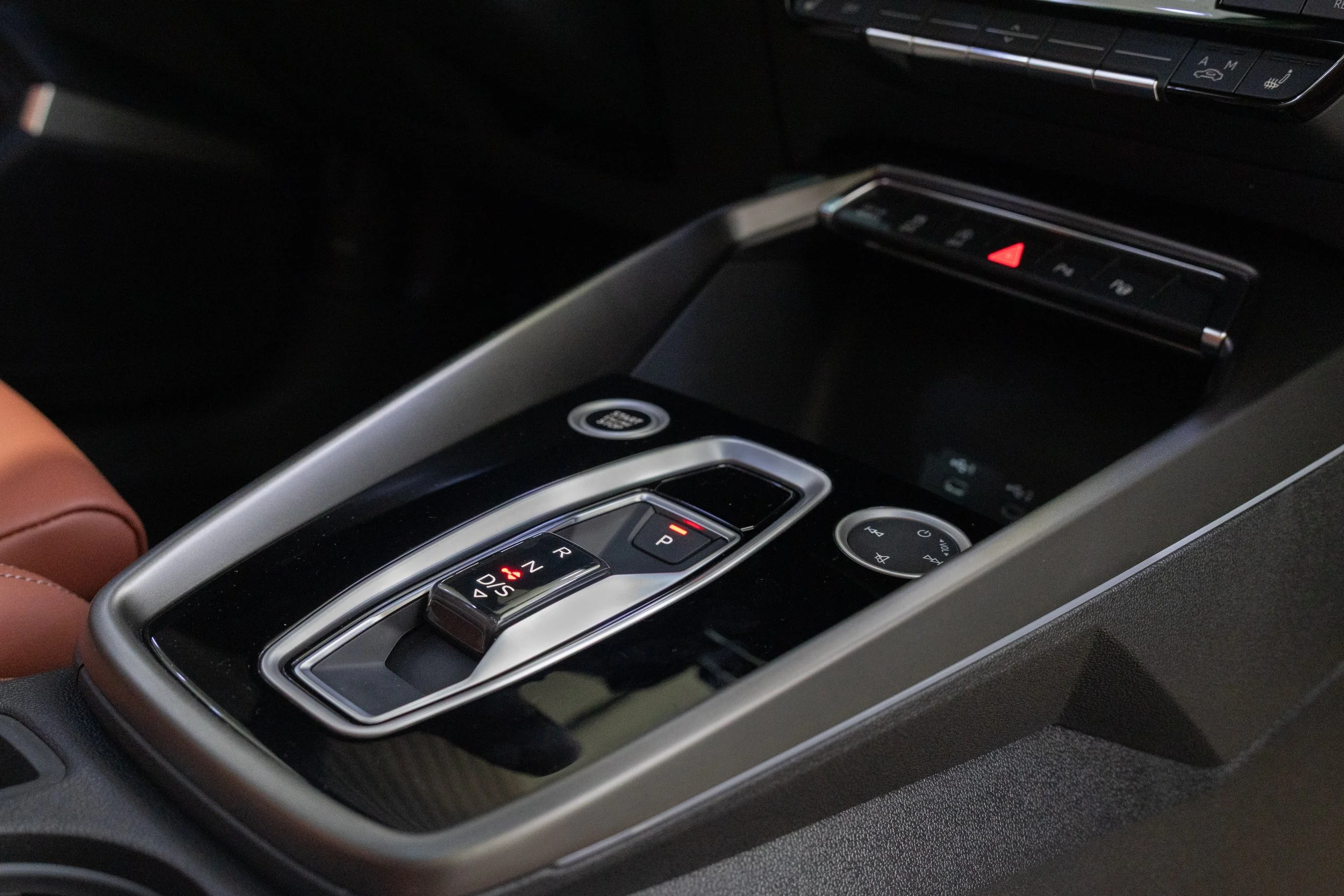 Close-up of a car's center console with gear shifter, hazard light button, and other controls.