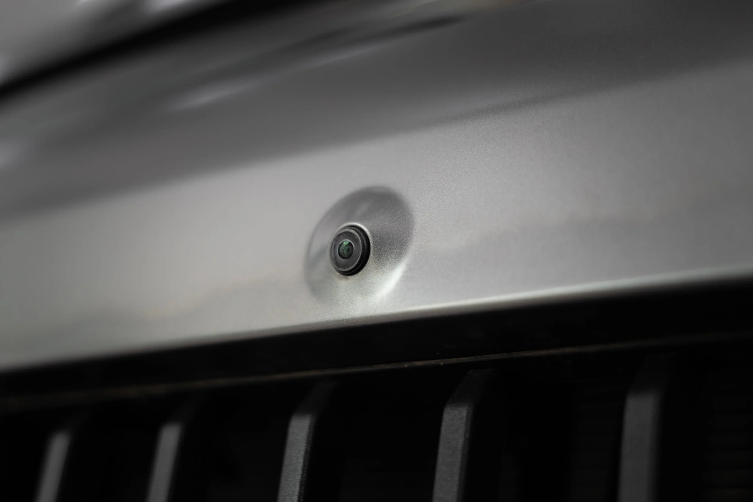 Close-up of a silver electronic device with a circular camera or sensor on its surface