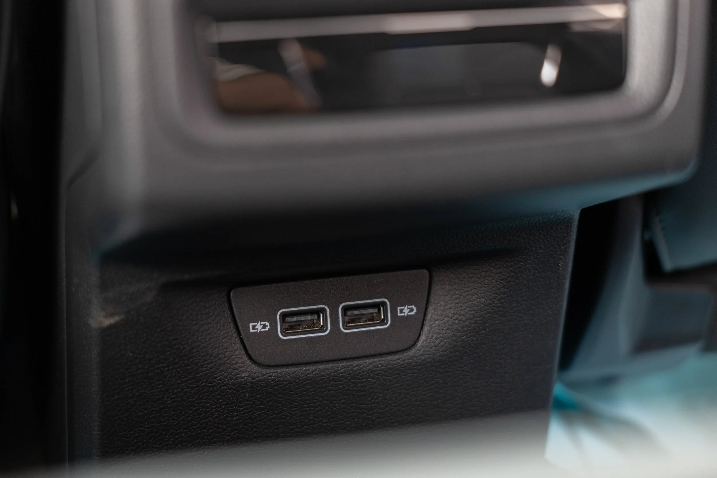 Close-up of a car's interior, showing a panel with two USB ports and a power outlet below the dashboard