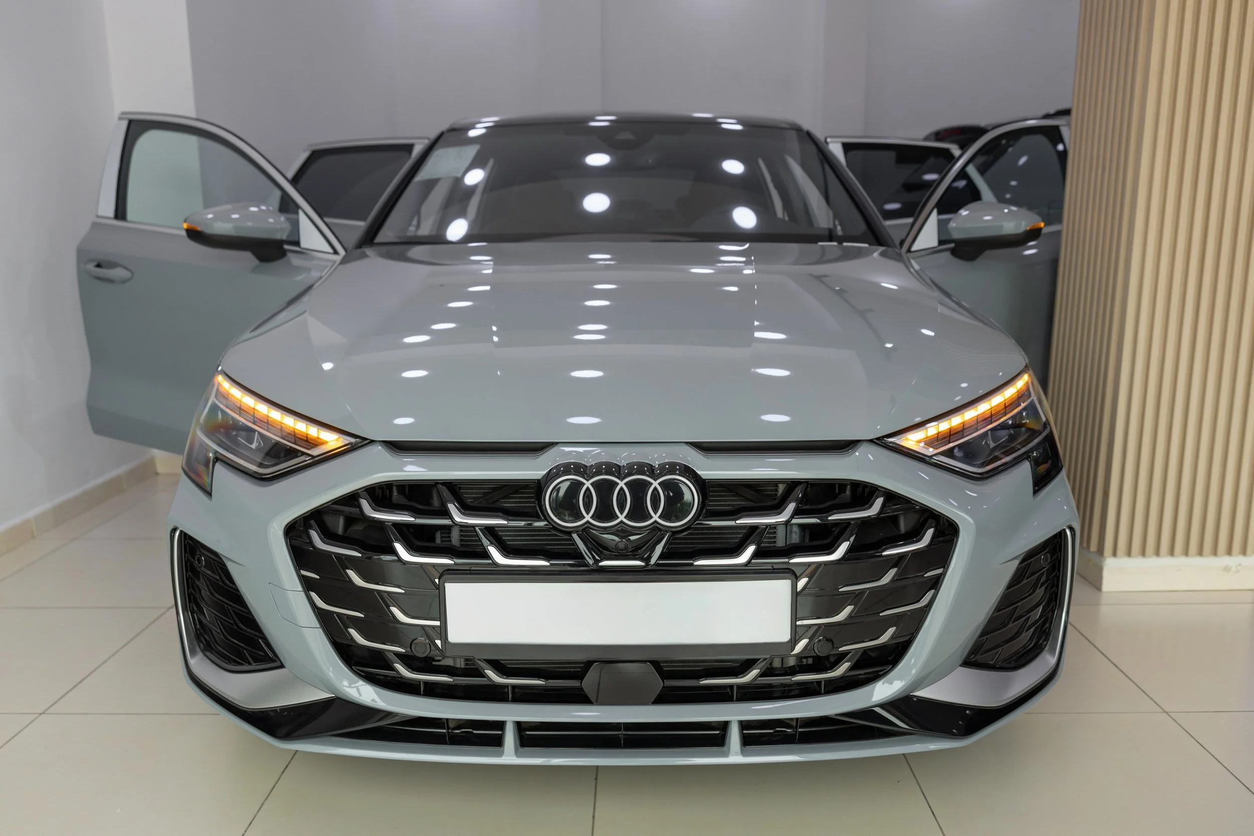 Voiture Audi grise exposée dans un showroom, vue de face avec portes ouvertes