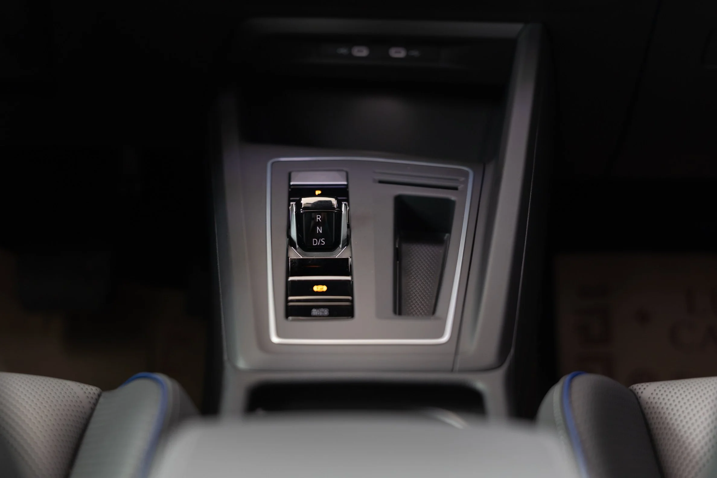 Close-up of a modern car's gear shift surrounded by control buttons, with gray and black interior accents.