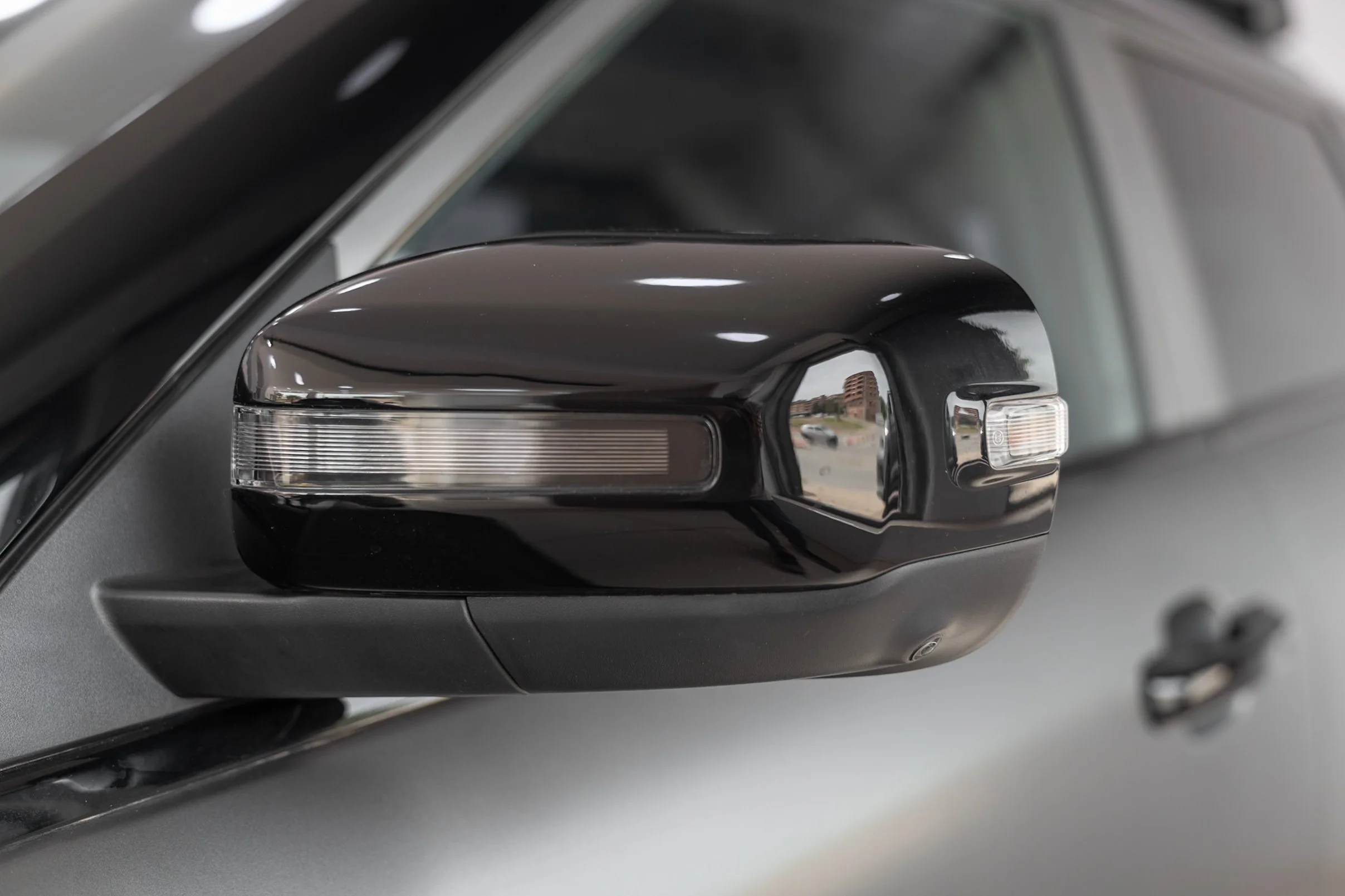 Close-up of a side mirror of a car, reflecting a building and a street scene.