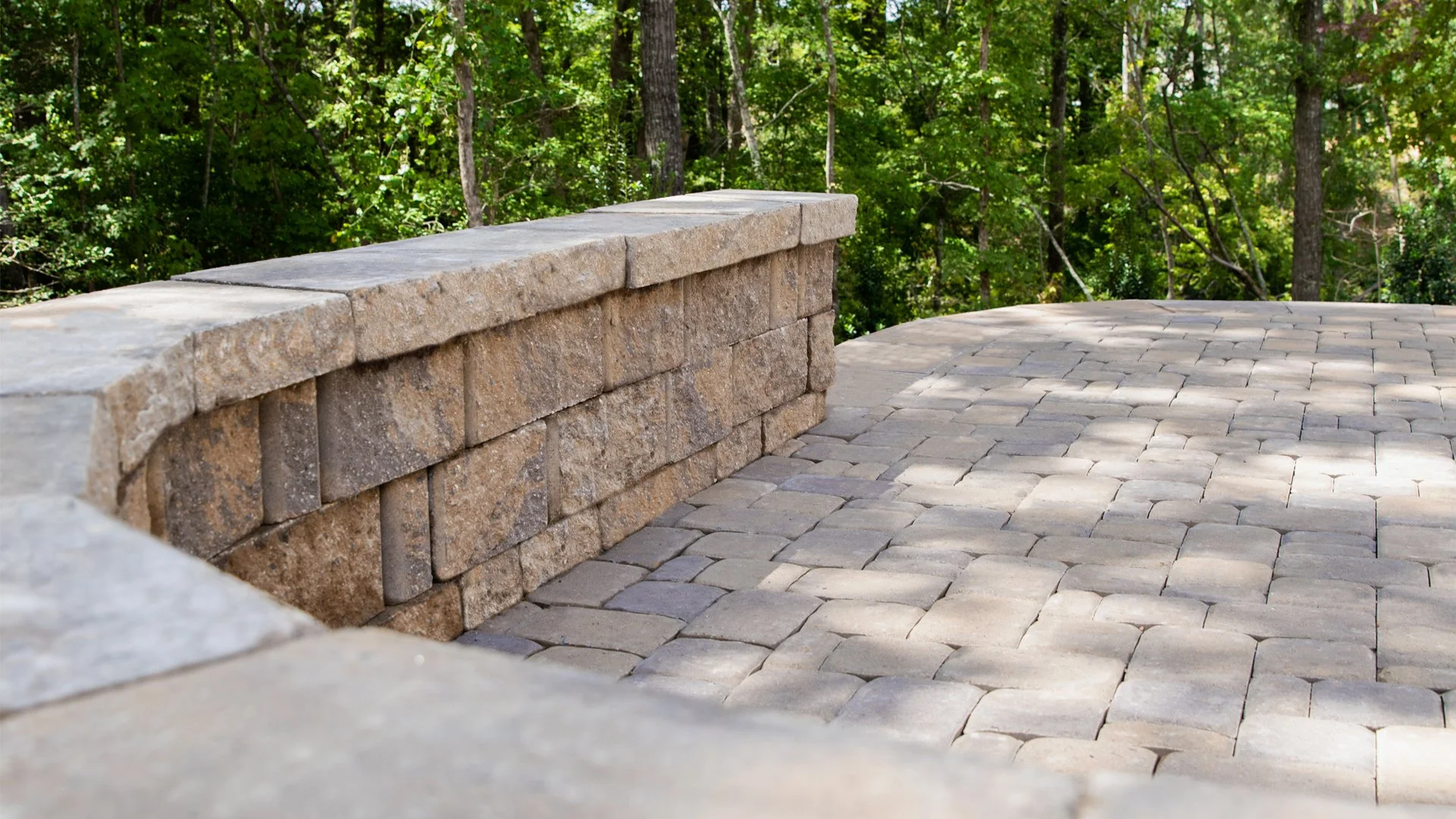 A stone sitting wall and paver patio installed by LOVING in Charlotte, NC.