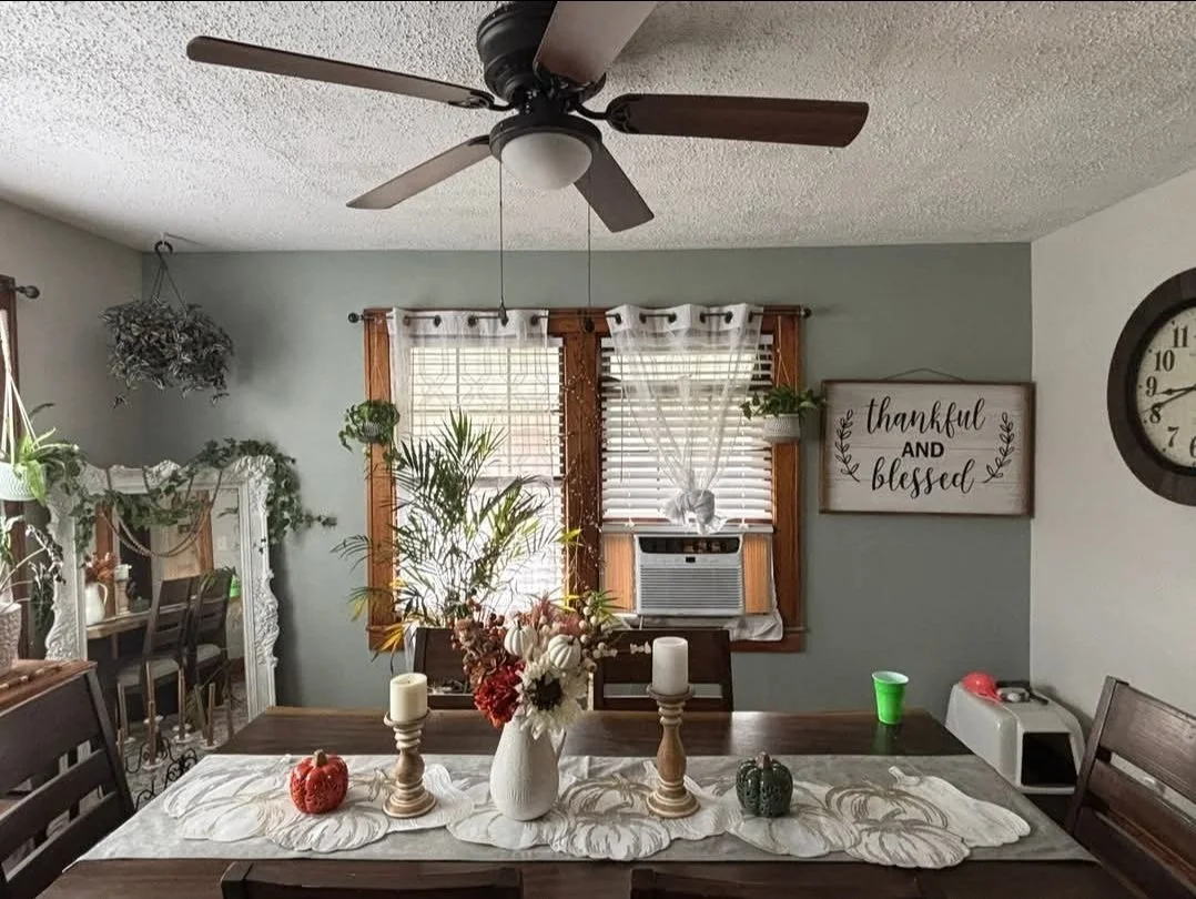 Dining room with window, clock, candles, flowers, and holiday decorations.