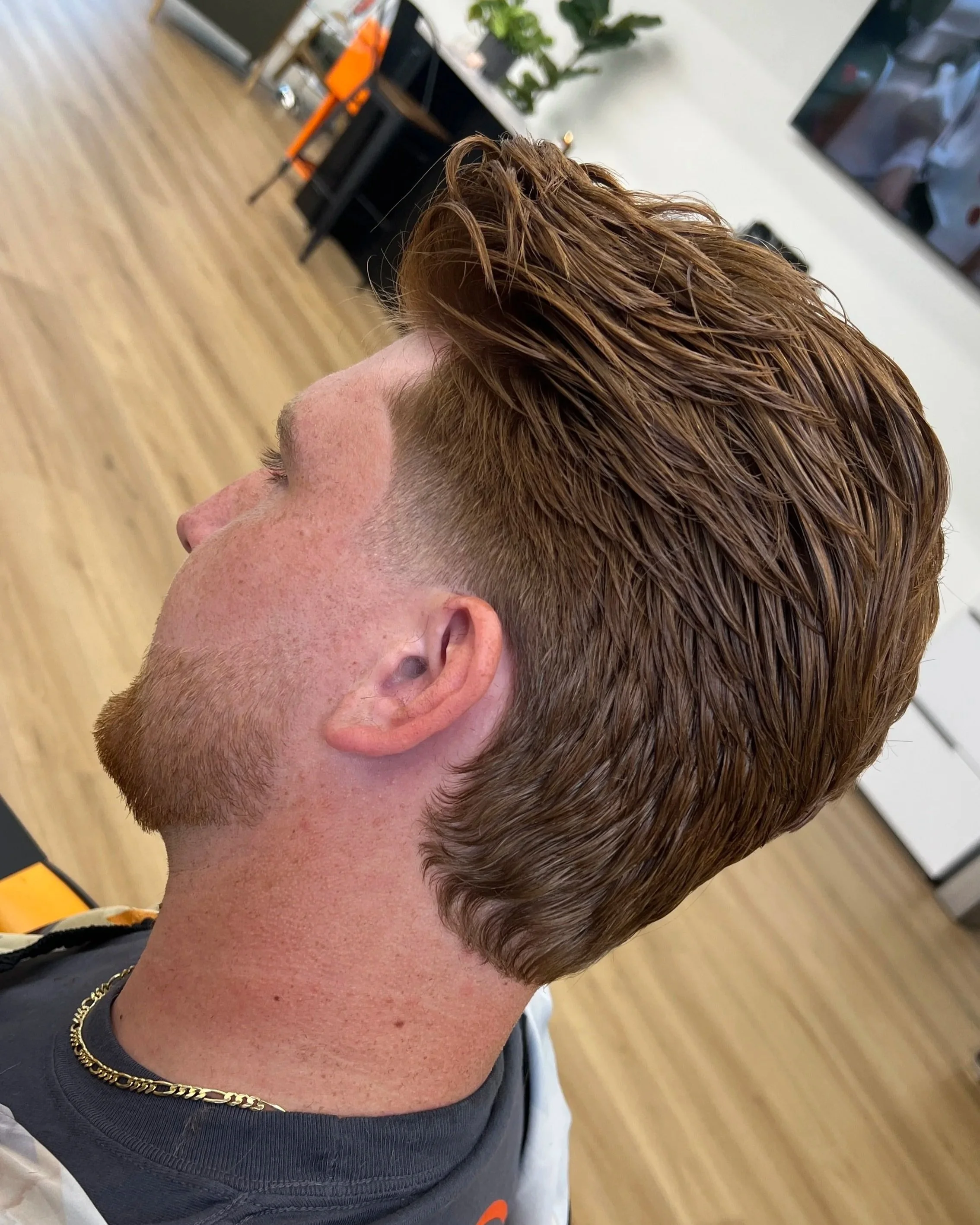 Slick back mens haircut with graduated layers , curtain bangs and a nature neck line. 