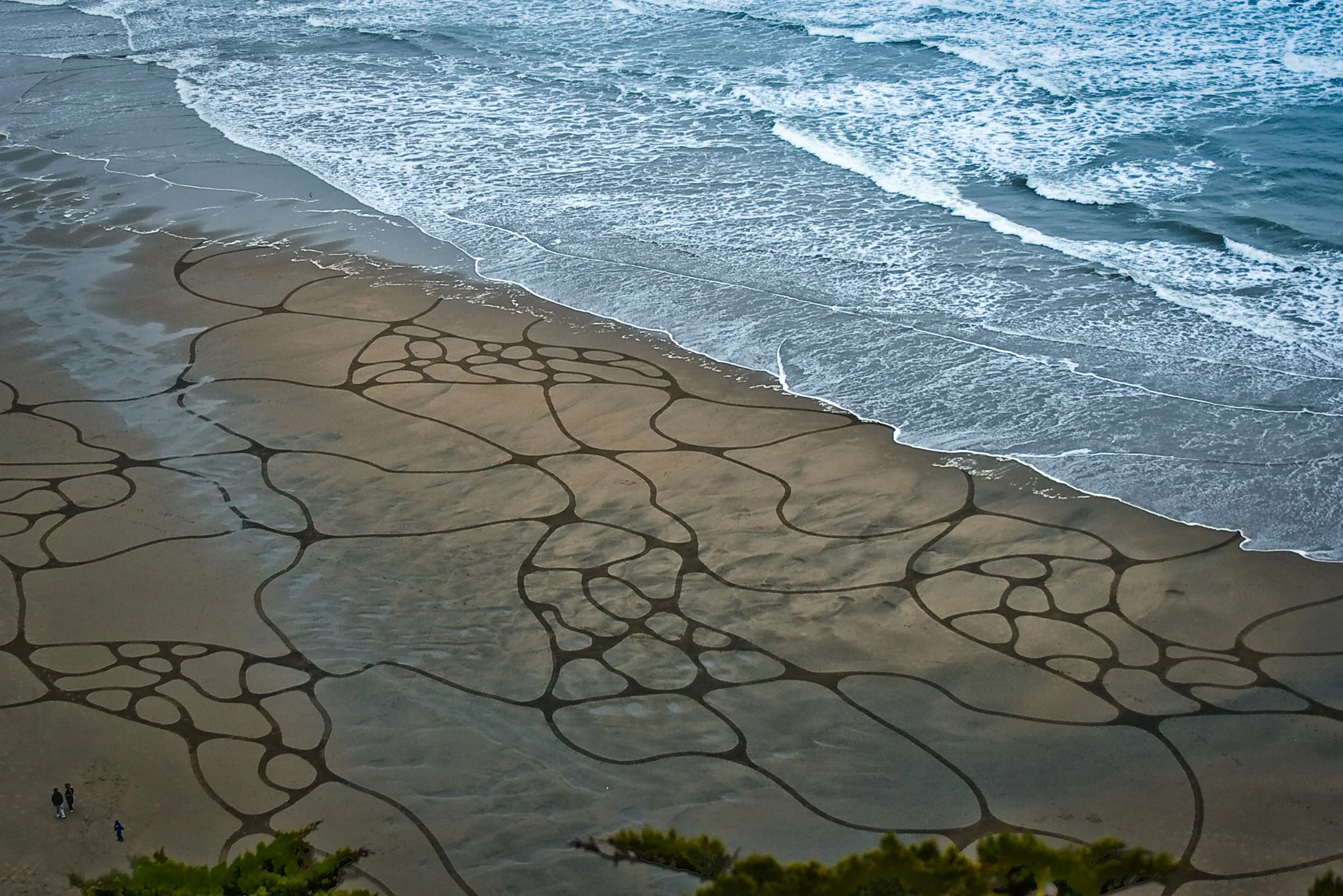 Beach with tide pools and waves crashing onto the shore, viewed from above.