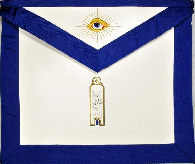 A white masonic apron with a blue border, featuring an eye within a sunburst at the top center and a gold outline of a plum, representing the Junior Warden underneath.
