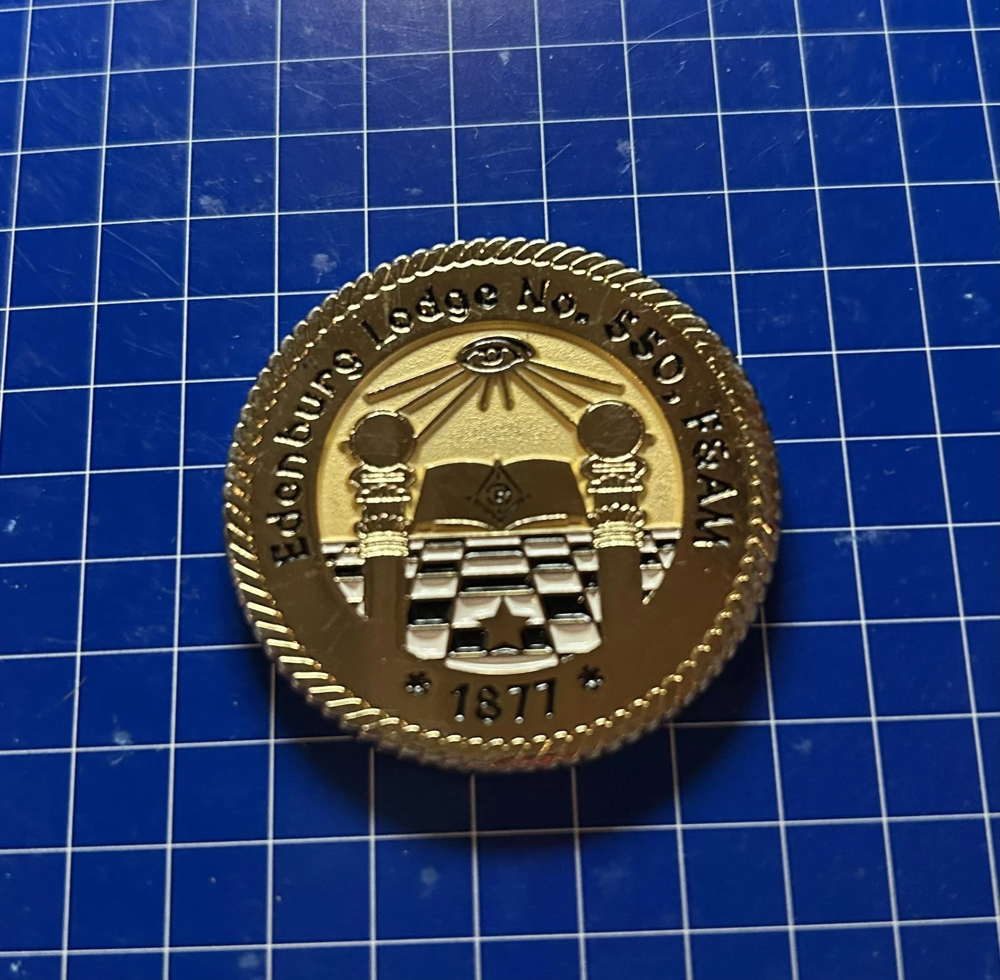 Gold coin medallion with the inscription "Eureka Lodge No. 350, F.&A.M., 1871" and Masonic symbols including an open book, square and compass, and rays of light.