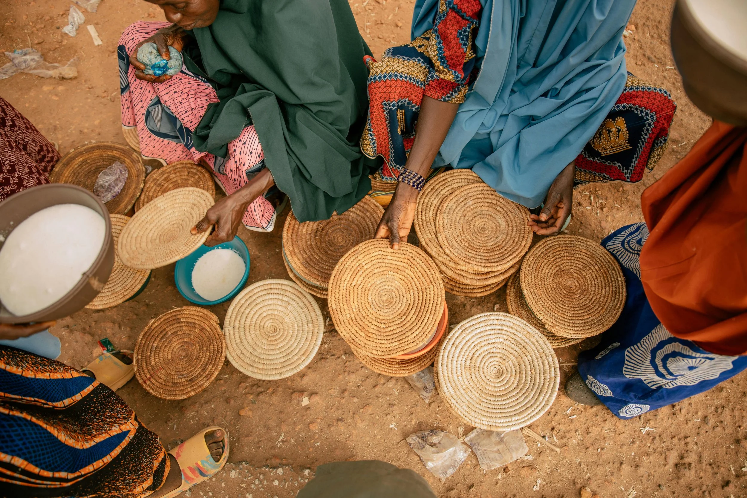 People selling woven baskets at an outdoor market.