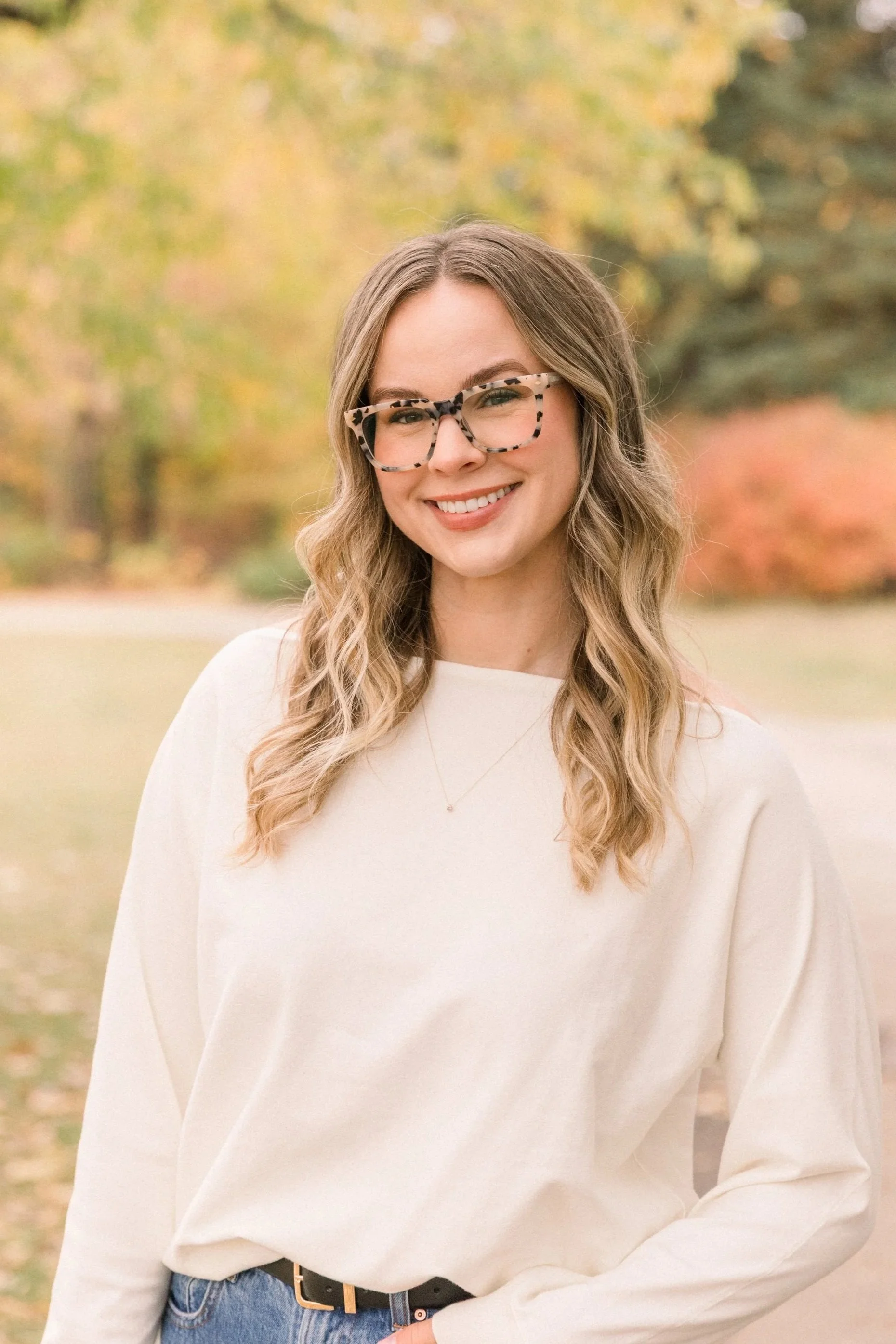 Friendly speech-language pathologist (SLP) MacKenzie Isaak is smiling outside on a fall day. Speech therapy in Saskatoon.